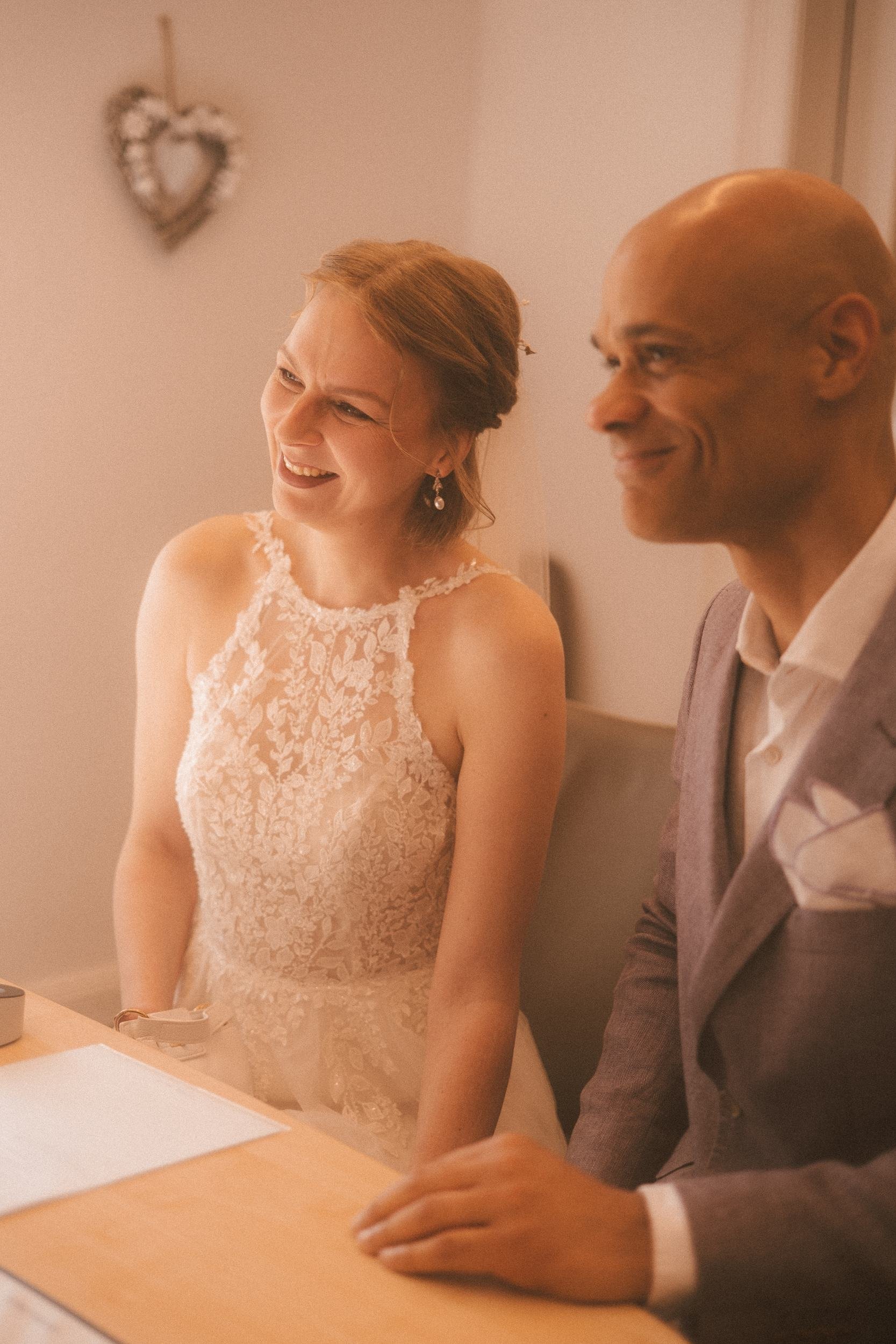 Couple laughing joyfully at the signing ceremony desk inside Berlin Standesamt registry office