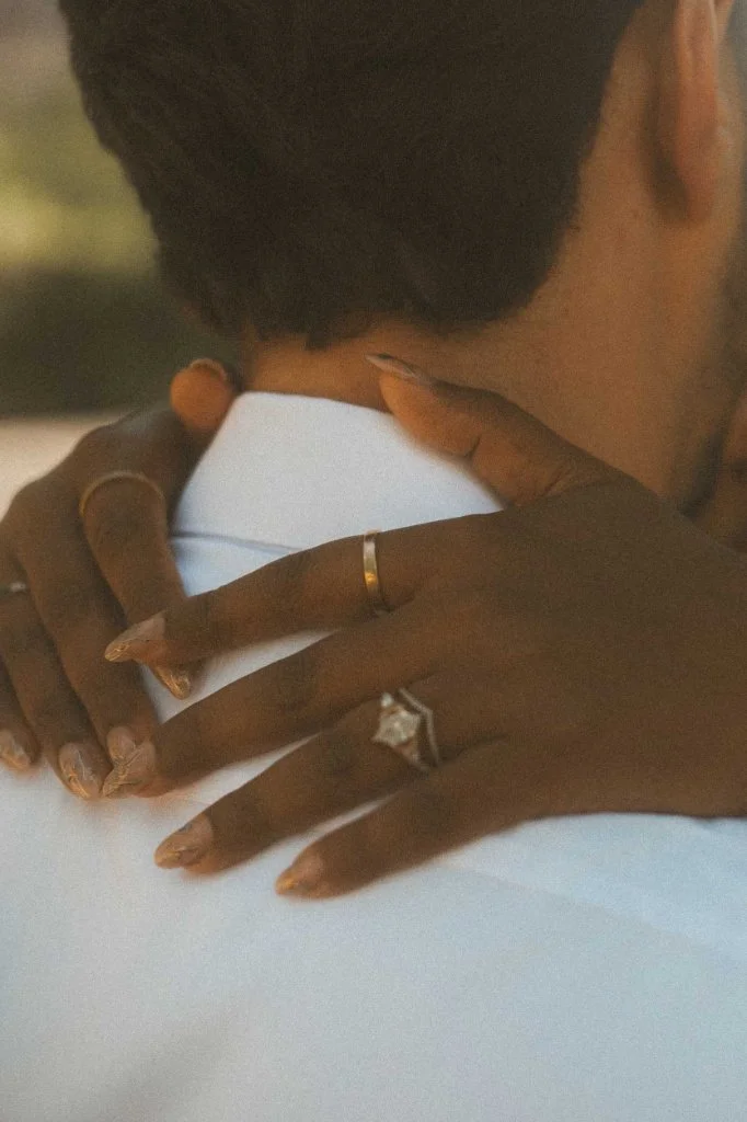 An intimate close-up of a partner's hands resting on their fiancé's shoulders, highlighting the engagement ring during a photoshoot in Berlin.