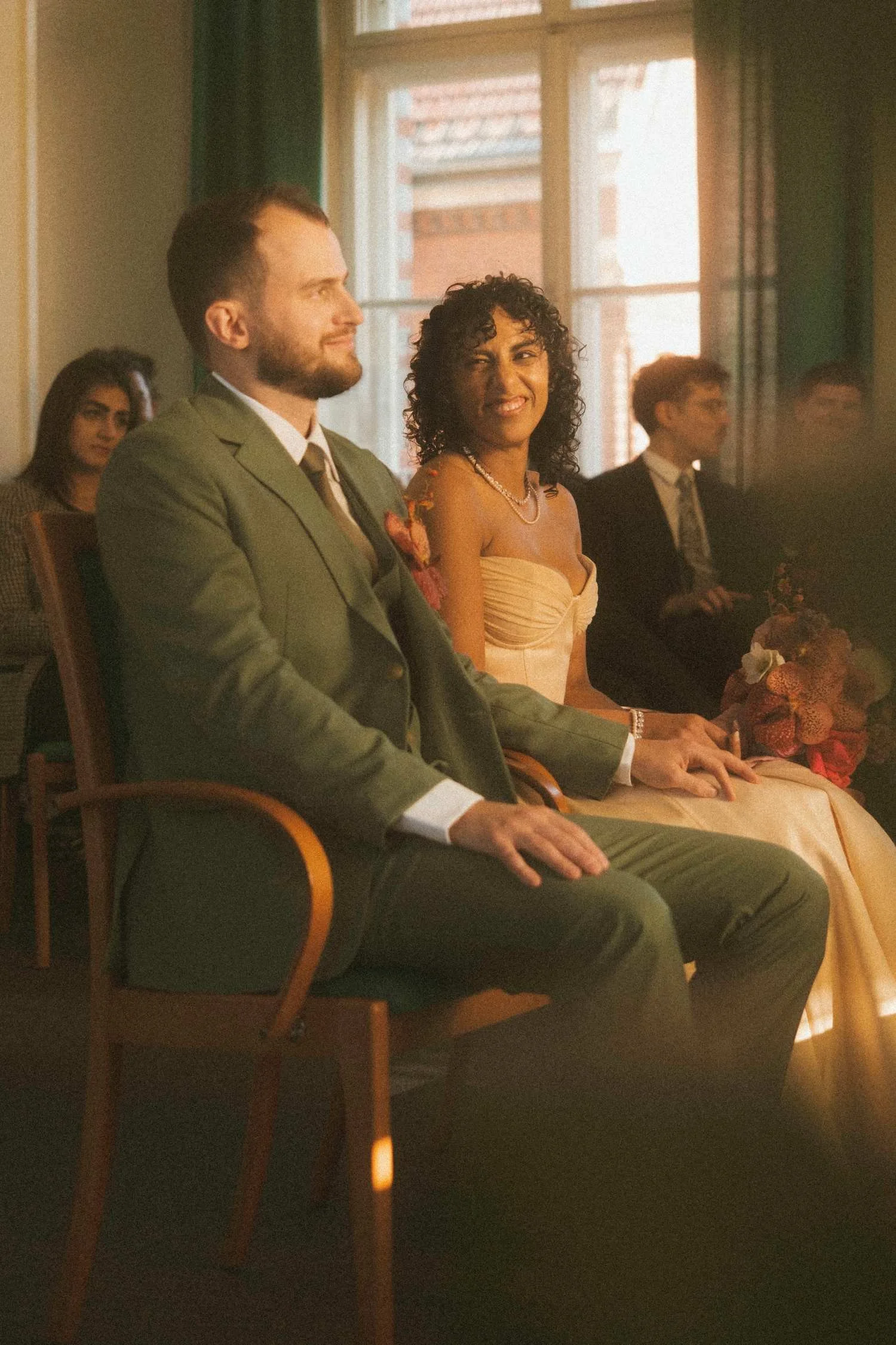 Bride smiling toward the groom as they sit together during a civil wedding ceremony at the Standesamt in Berlin
