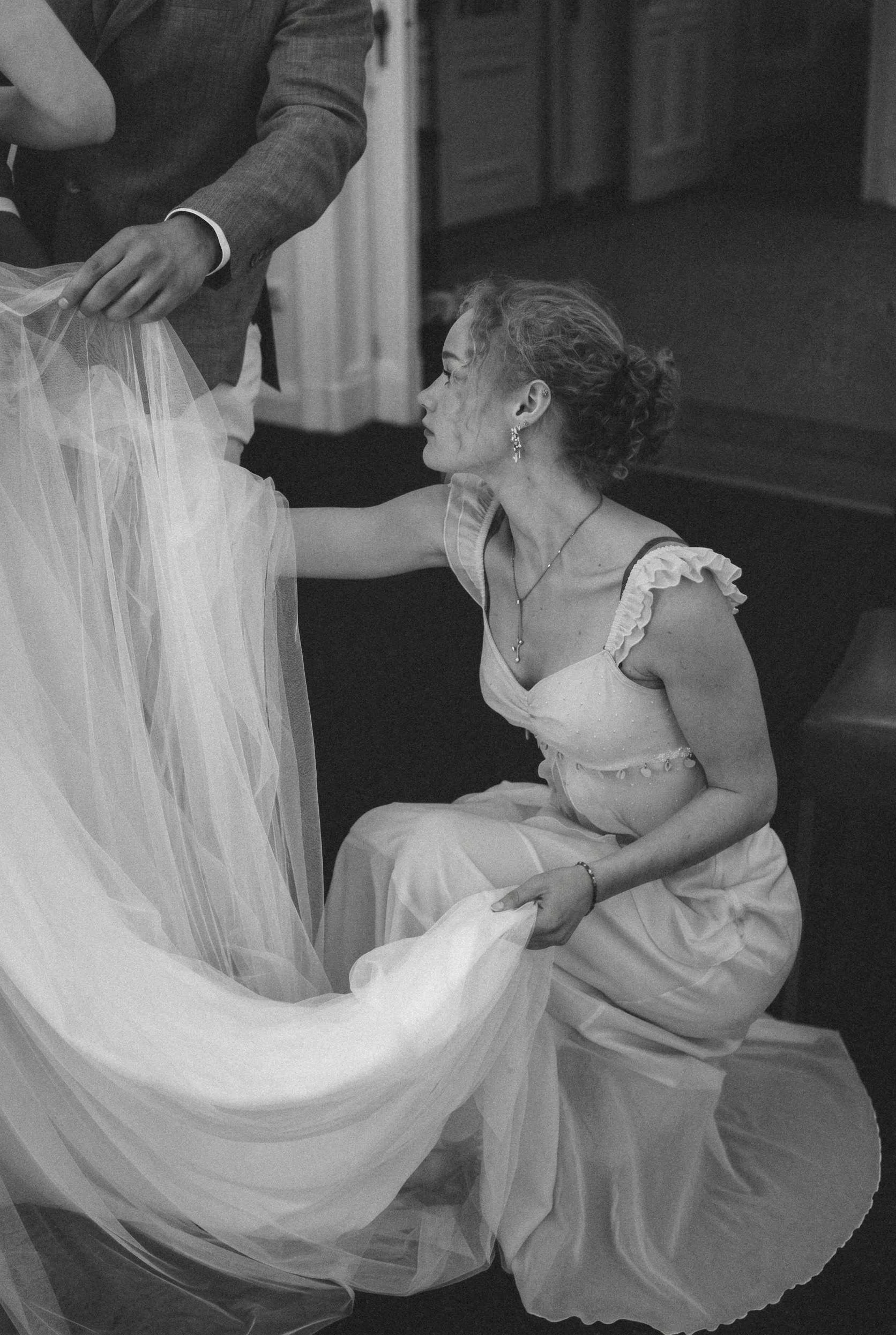 Woman kneeling to adjust bride's dress train and veil at Berlin Standesamt civil ceremony