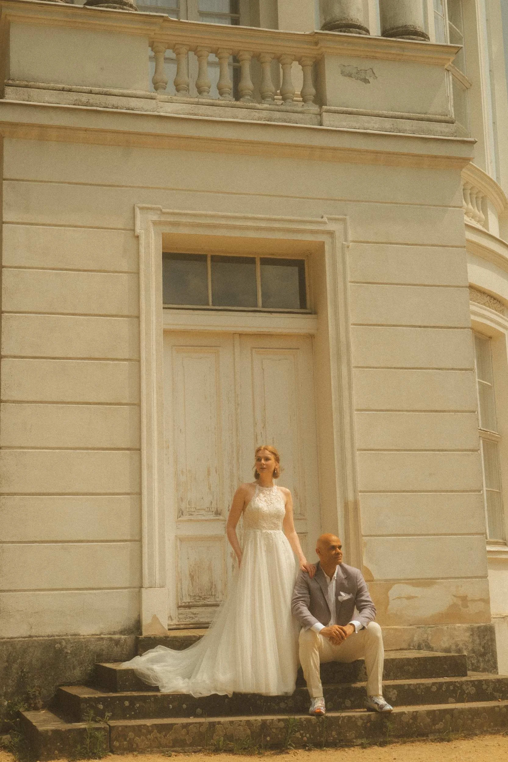 Couple posing on exterior steps of ornate Berlin Standesamt building with bride standing in doorway