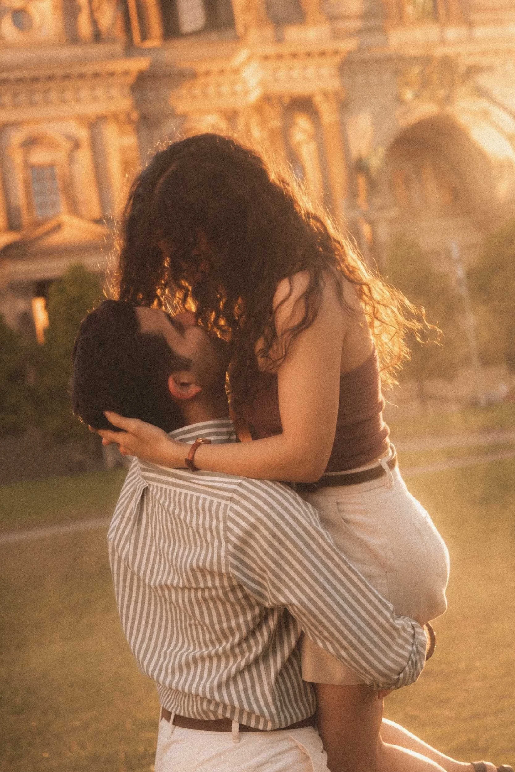 A man lifting his partner in a romantic embrace during an engagement photoshoot at golden hour in front of the Bode Museum in Berlin.