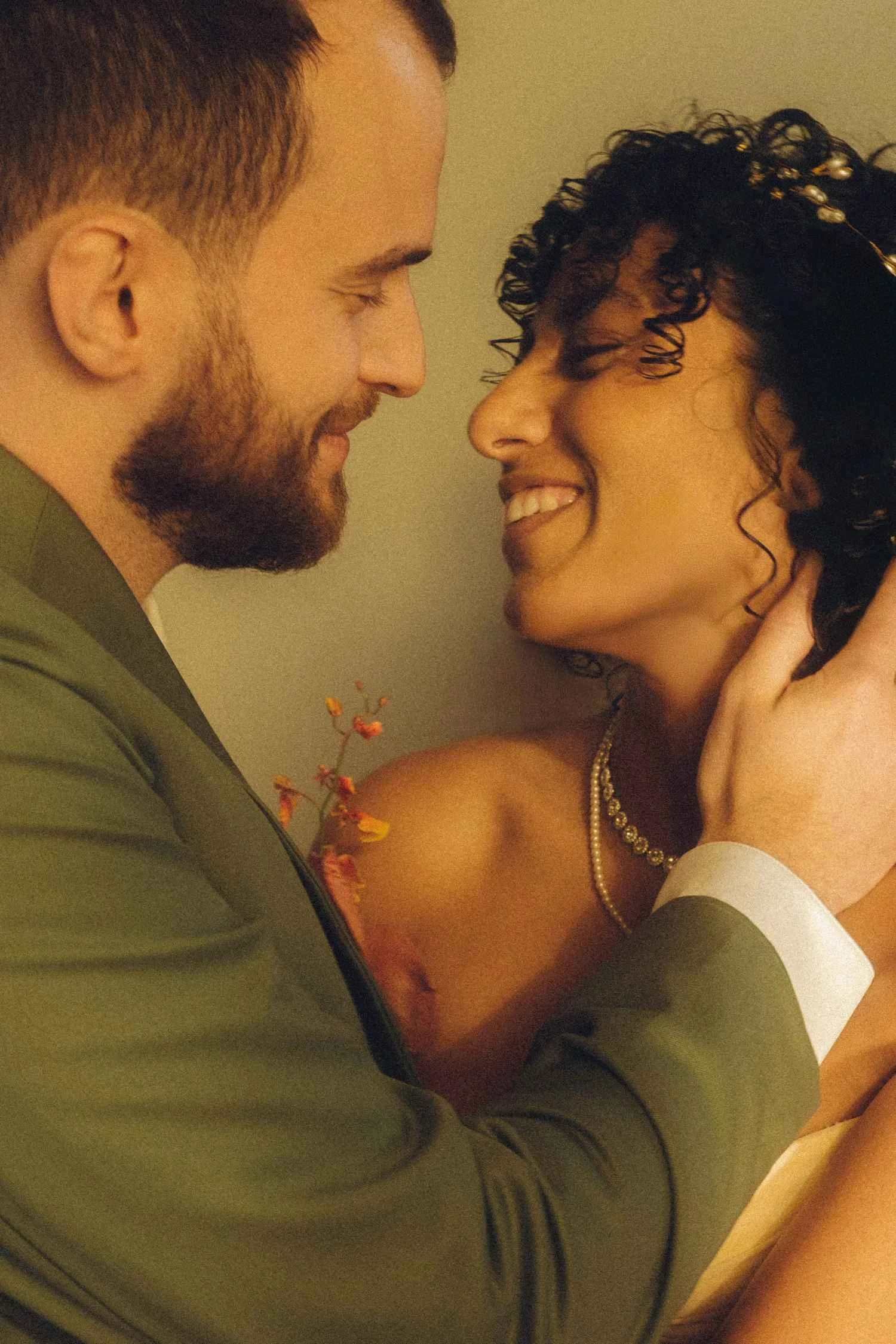 Close-up of a bride and groom smiling at each other, faces close together in a quiet, intimate moment.