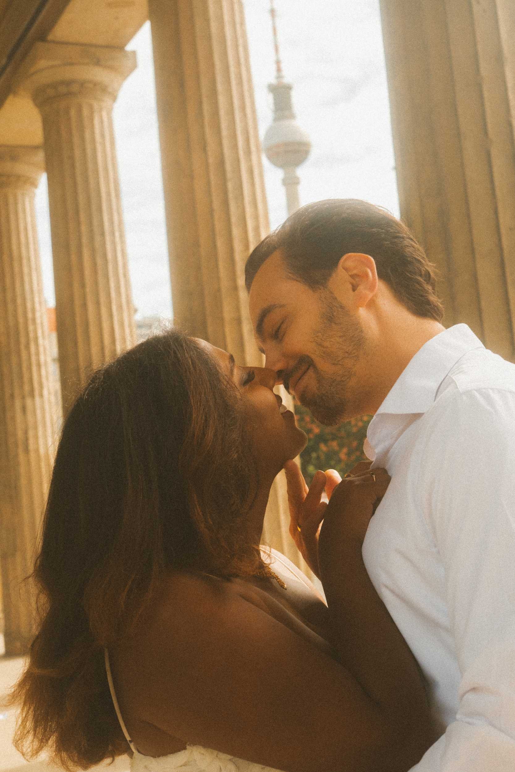 An intimate close-up shot of a couple about to share a kiss during an engagement photoshoot in Berlin, with the iconic TV Tower visible in the background.