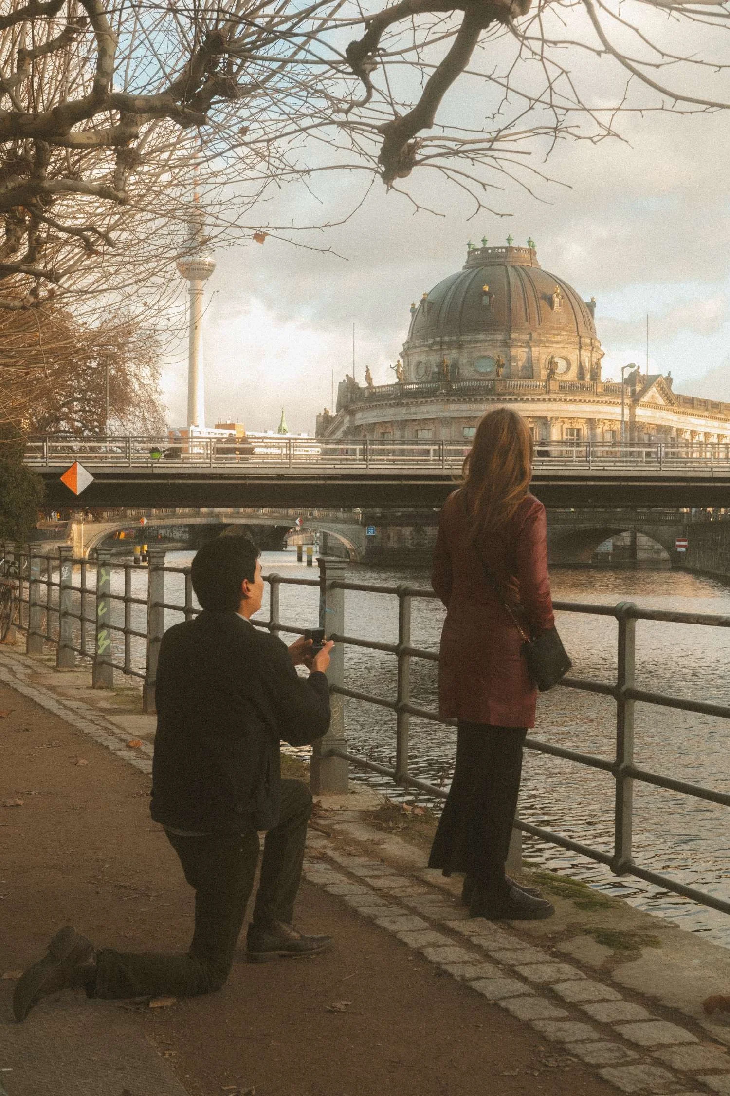 Surprise marriage proposal by the River Spree with Bode Museum and Berlin skyline in the background