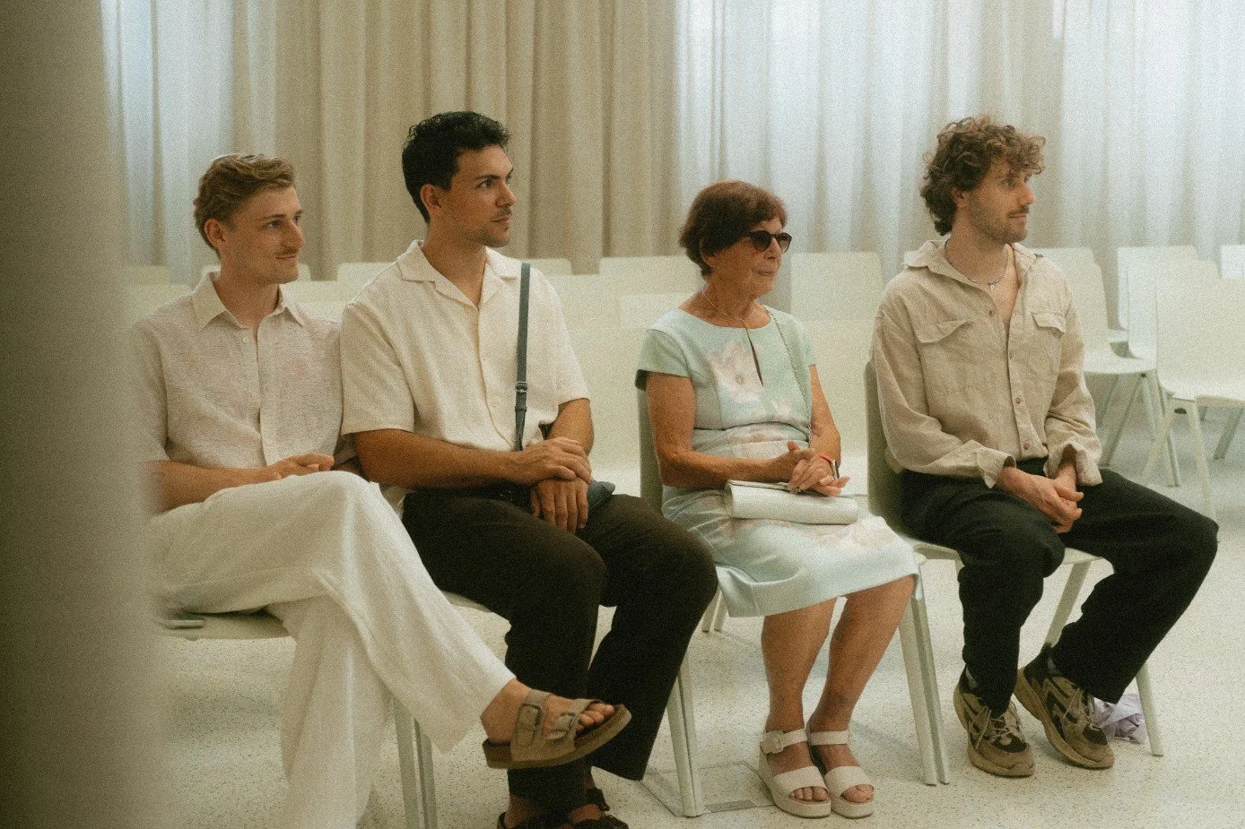 A group of wedding guests seated together watching an indoor ceremony.
