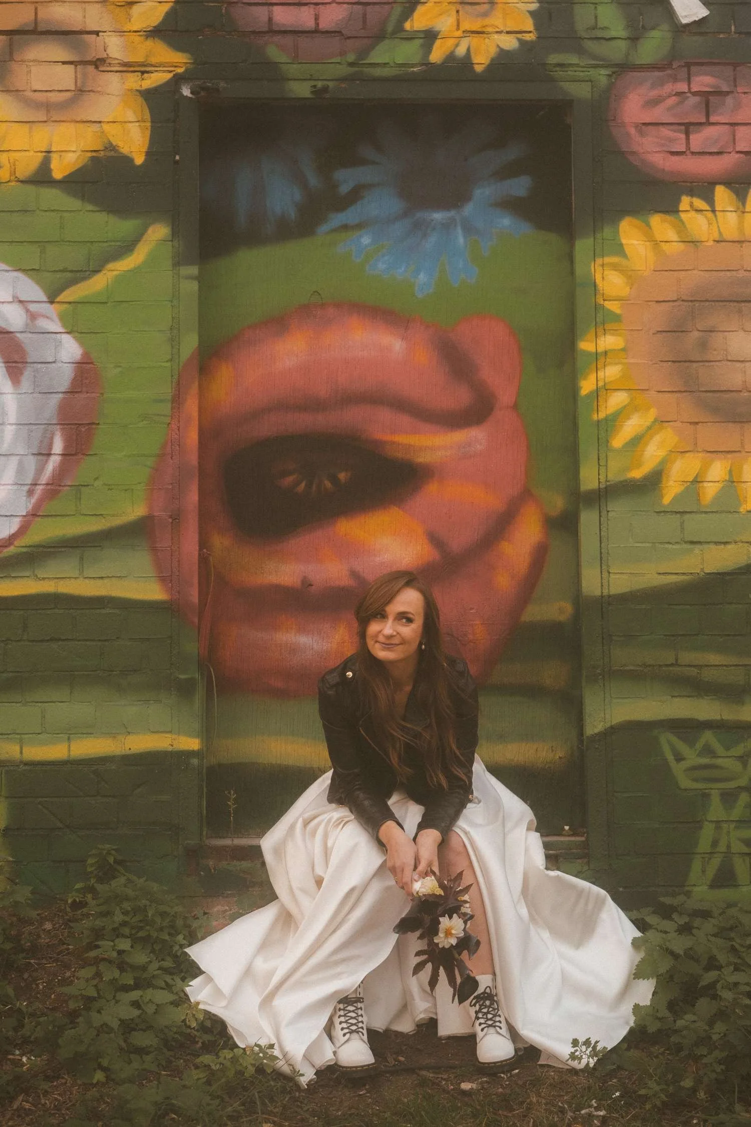 Bride sitting in front of colorful graffiti wall during wedding photoshoot at Teufelsberg Berlin