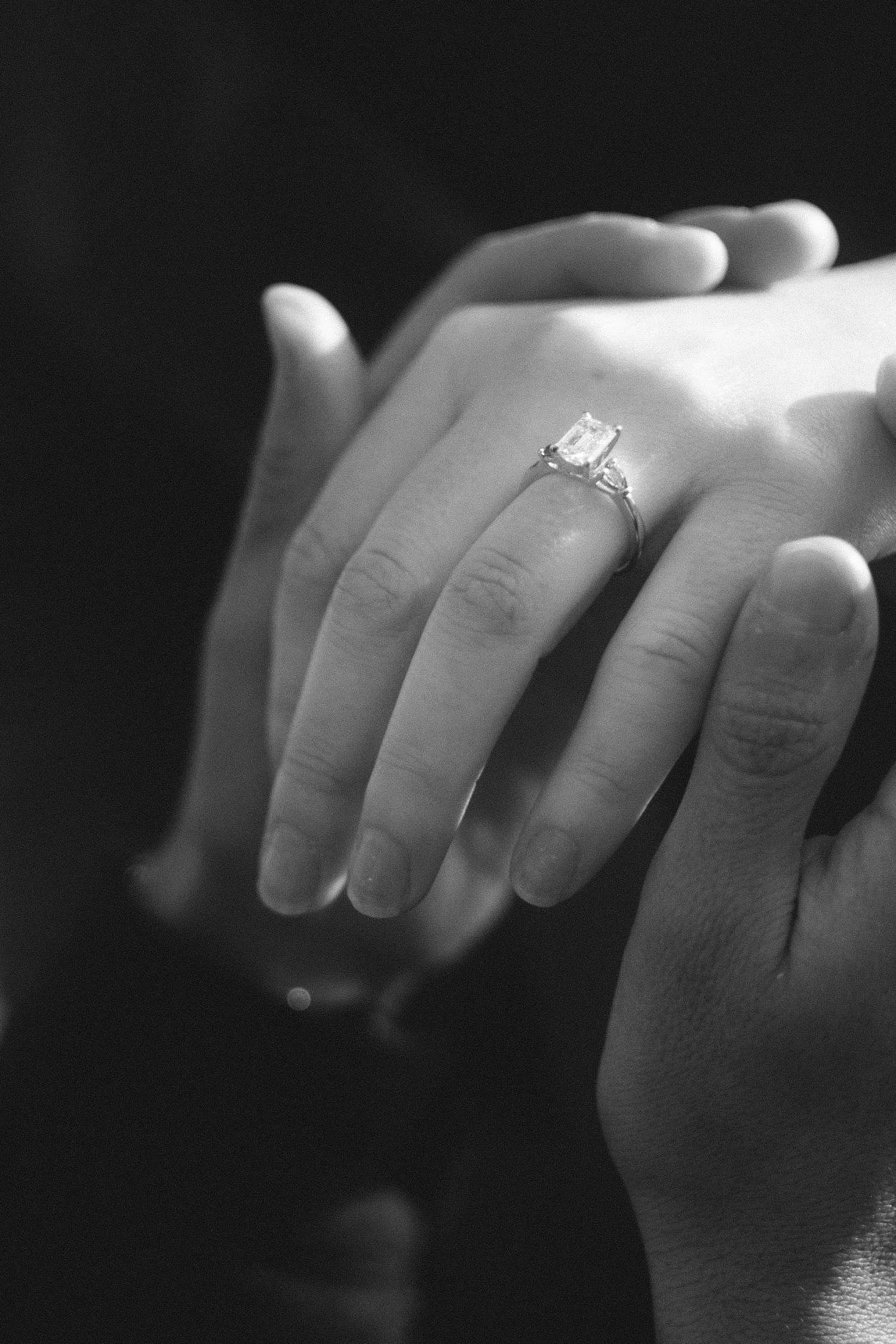Black and white close-up of an engagement ring on a woman’s hand, held by her partner, photographed in Berlin.