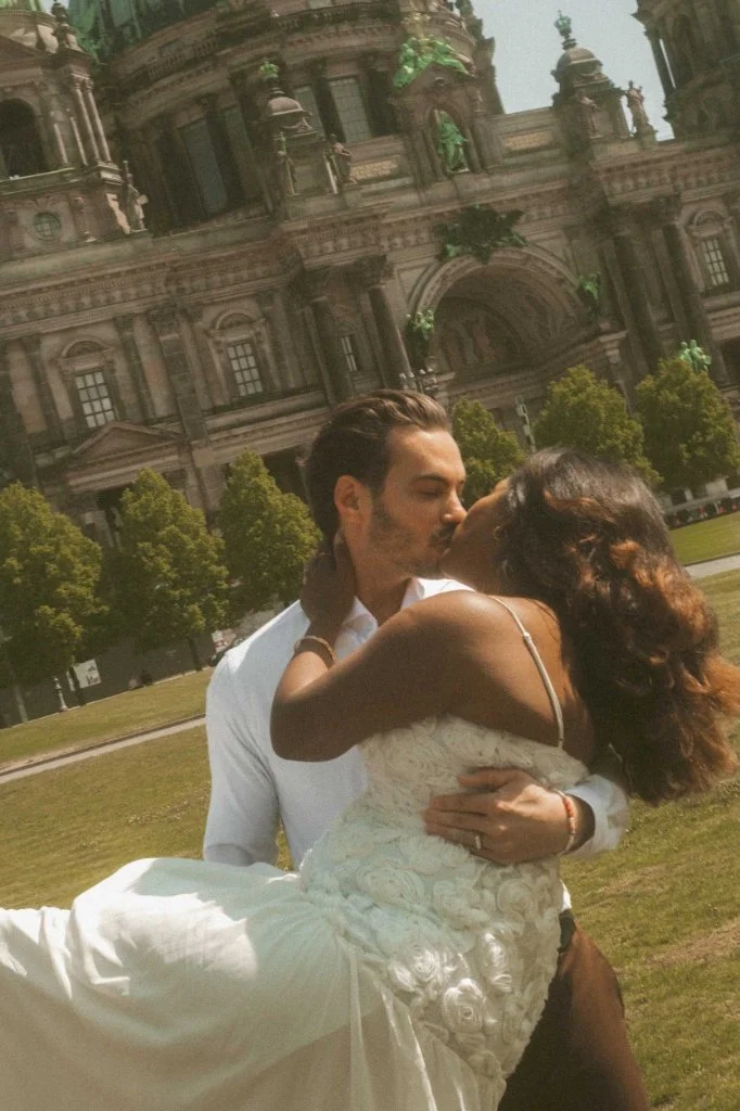A romantic engagement photoshoot in Berlin featuring a couple sharing a kiss while the groom lifts the bride in front of the iconic Berliner Dom Cathedral.