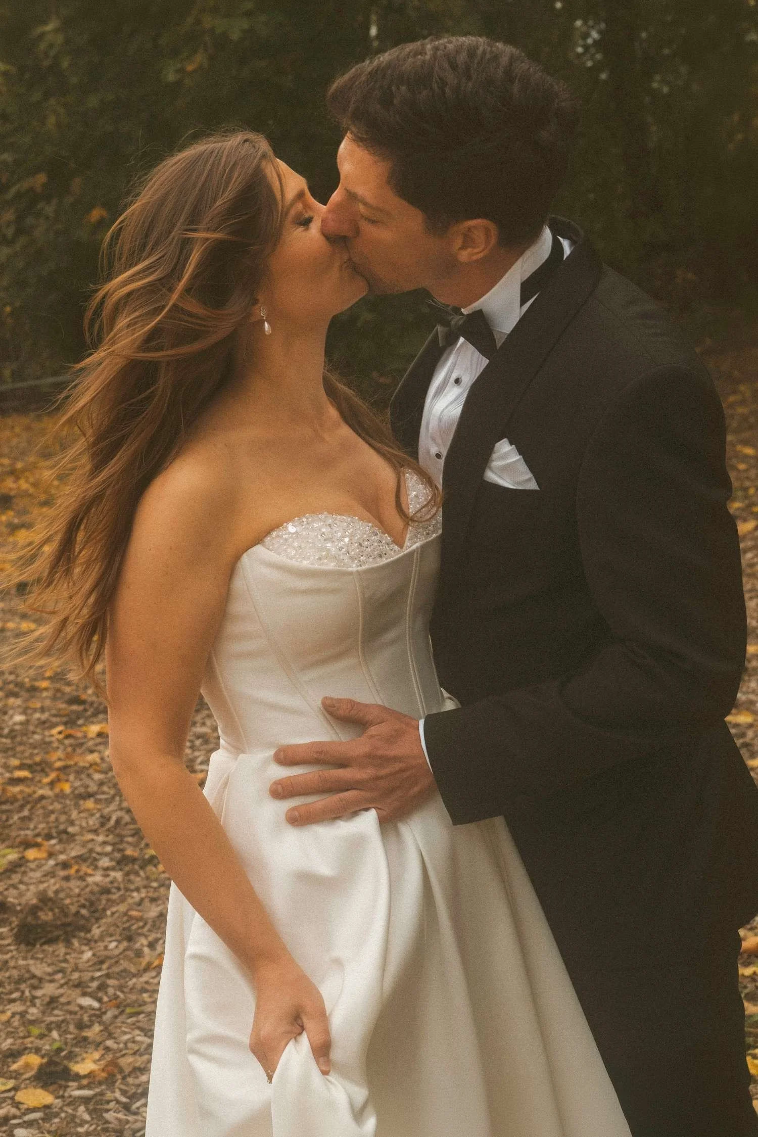 Bride and groom kissing during autumn wedding photoshoot at Teufelsberg Berlin with golden leaves