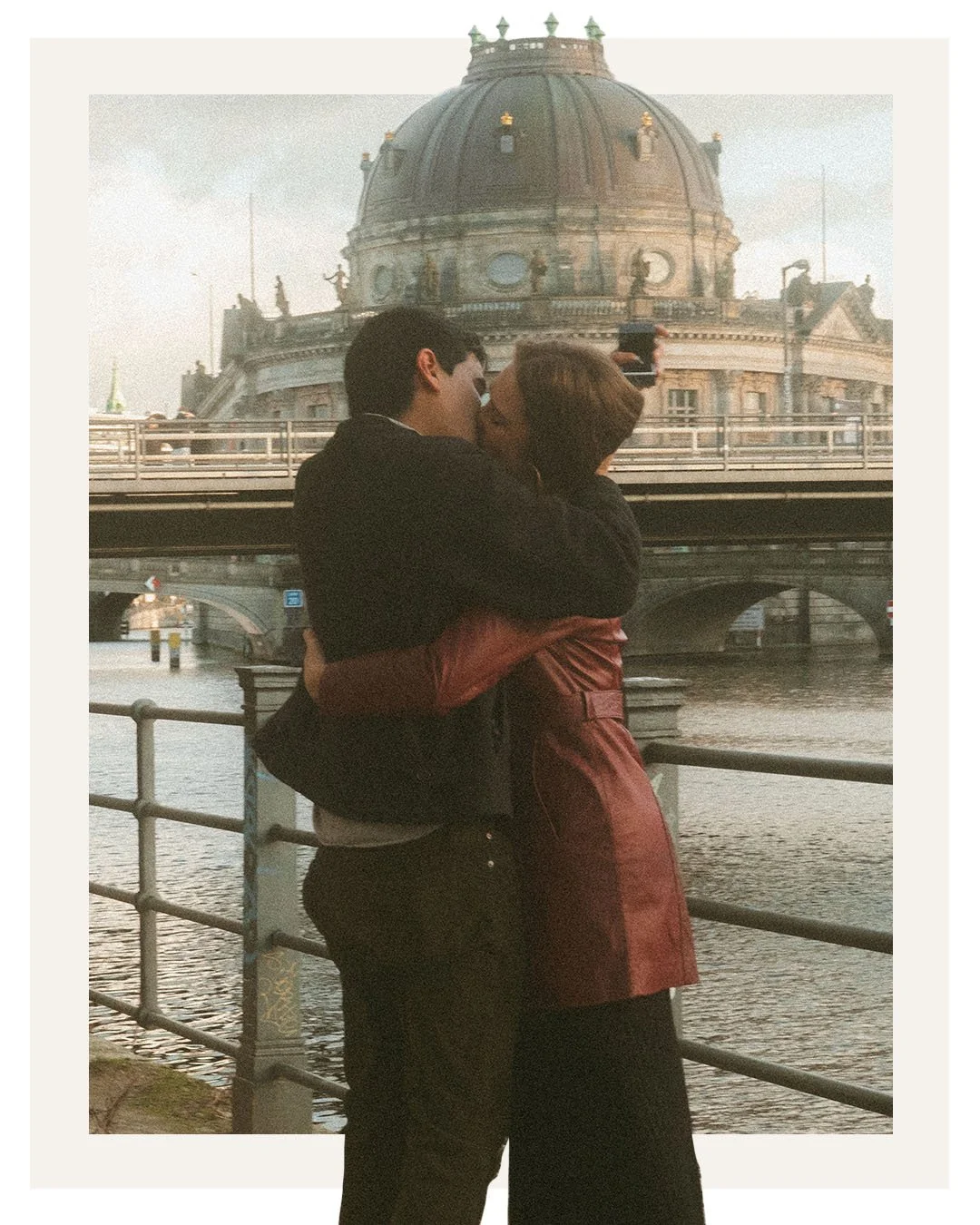 Romantic couple kissing by the river in front of Bode Museum on Museum Island in Berlin.