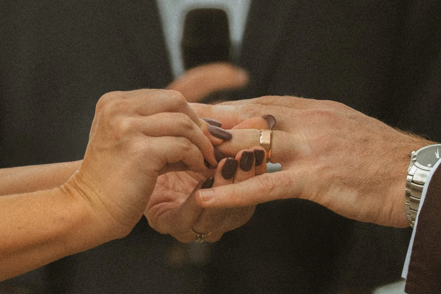 Close-up of hands during wedding ceremony as rings are exchanged between couple