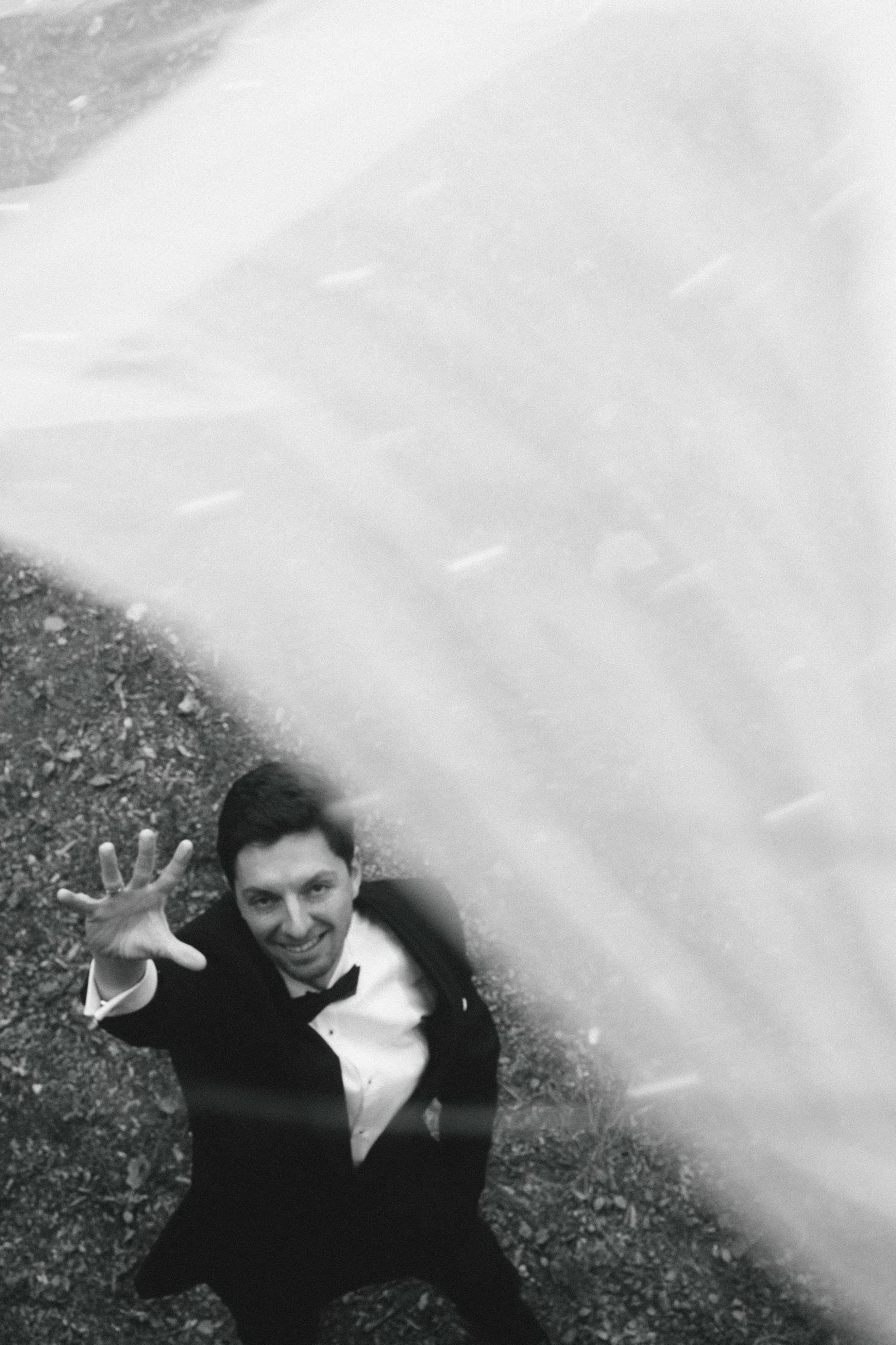 Black and white creative portrait of groom reaching up during wedding photoshoot at Teufelsberg Berlin
