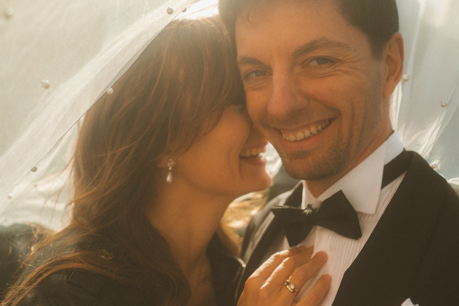 Bride whispering to groom under veil during golden hour wedding photoshoot at Teufelsberg Berlin
