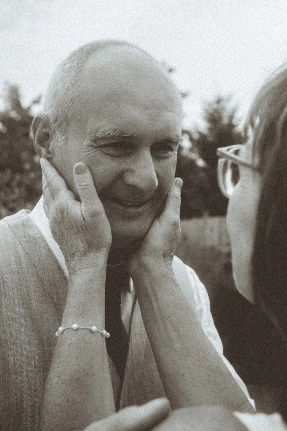 A close-up black and white outdoor portrait of the bride gently holding the groom's face in her hands.