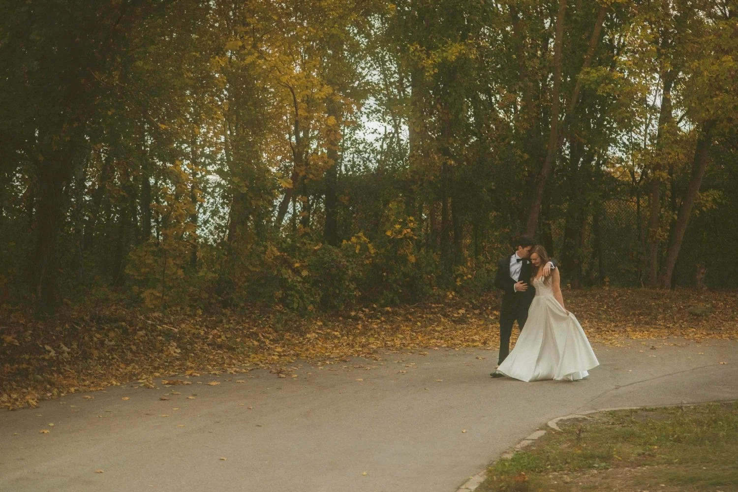 Bride and groom walking together on tree-lined path at Teufelsberg Berlin during autumn wedding photoshoot