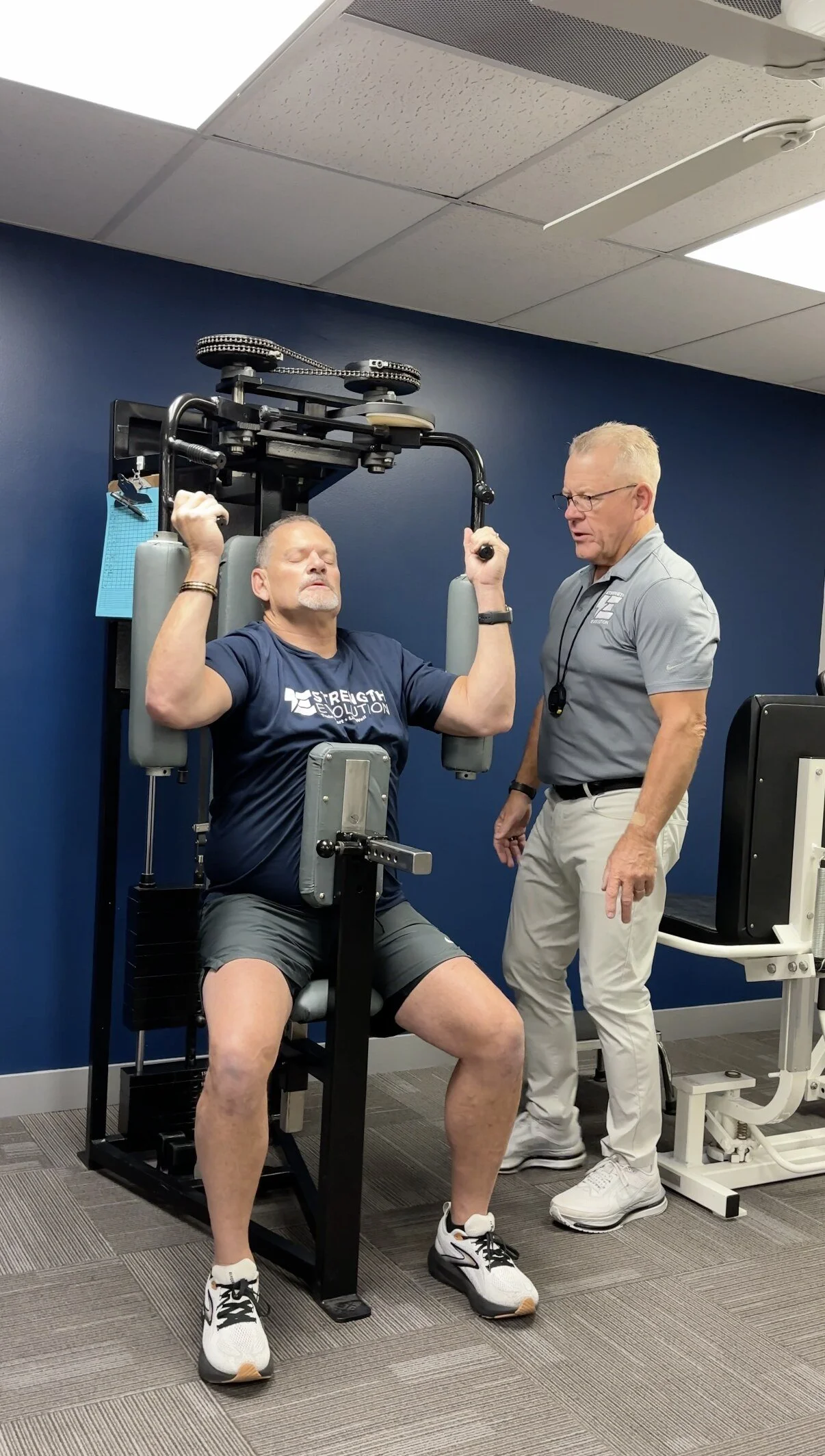 Trainer coaching a client on a chest machine at Strength Evolution Madison