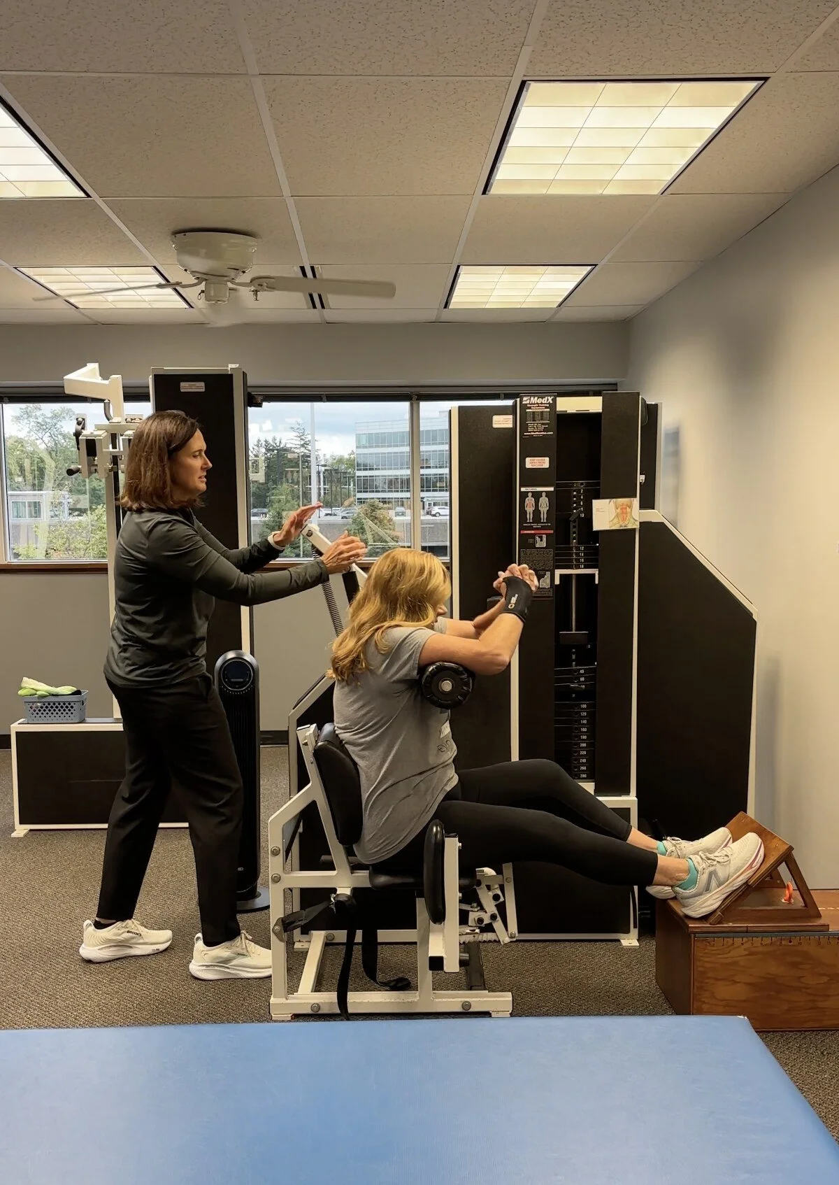 Trainer coaching a client on a MedX machine at Strength Evolution Wauwatosa