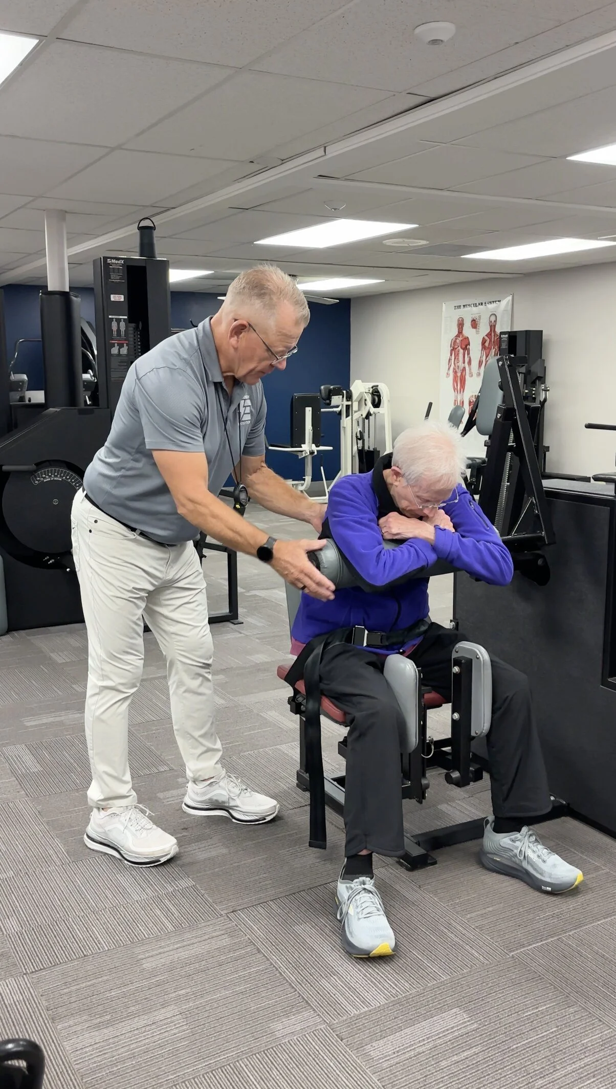 Trainer guiding a client's form on a MedX machine at Strength Evolution Madison