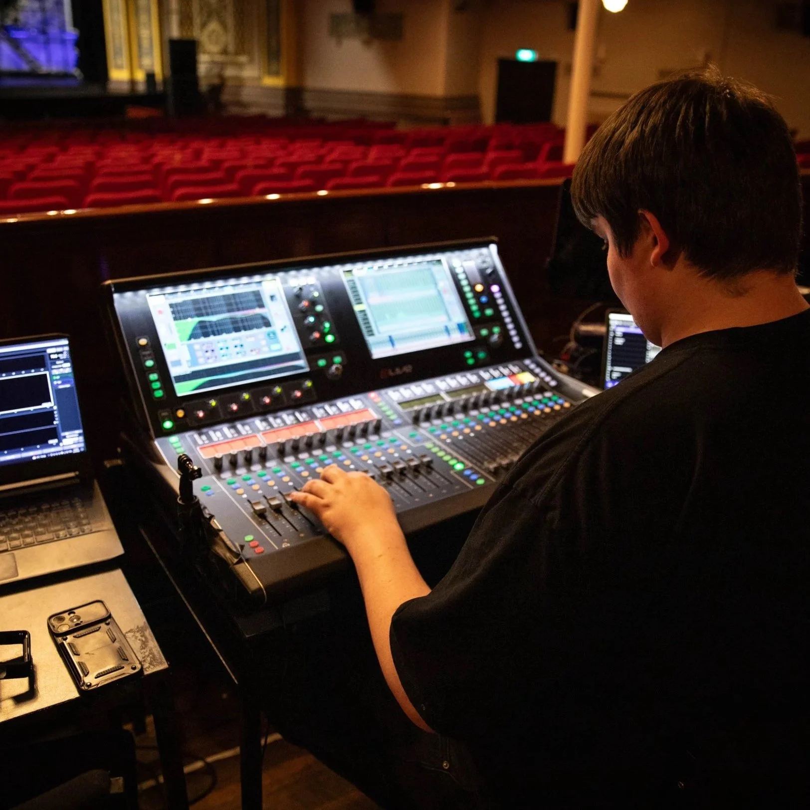 Person operating a sound mixing console in a theater.