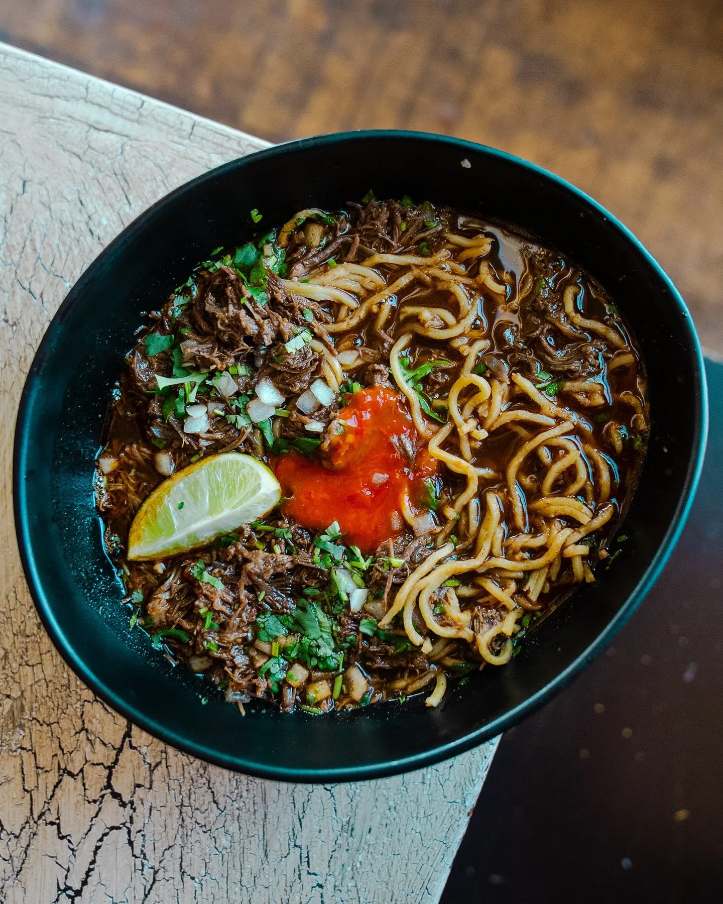 PSA. Birria Ramen is here. Fresh ramen noodles, slow-cooked shredded beef, consomm&eacute;, onion, cilantro, lime, and sambal. Limited time as part of our seasonal menu.