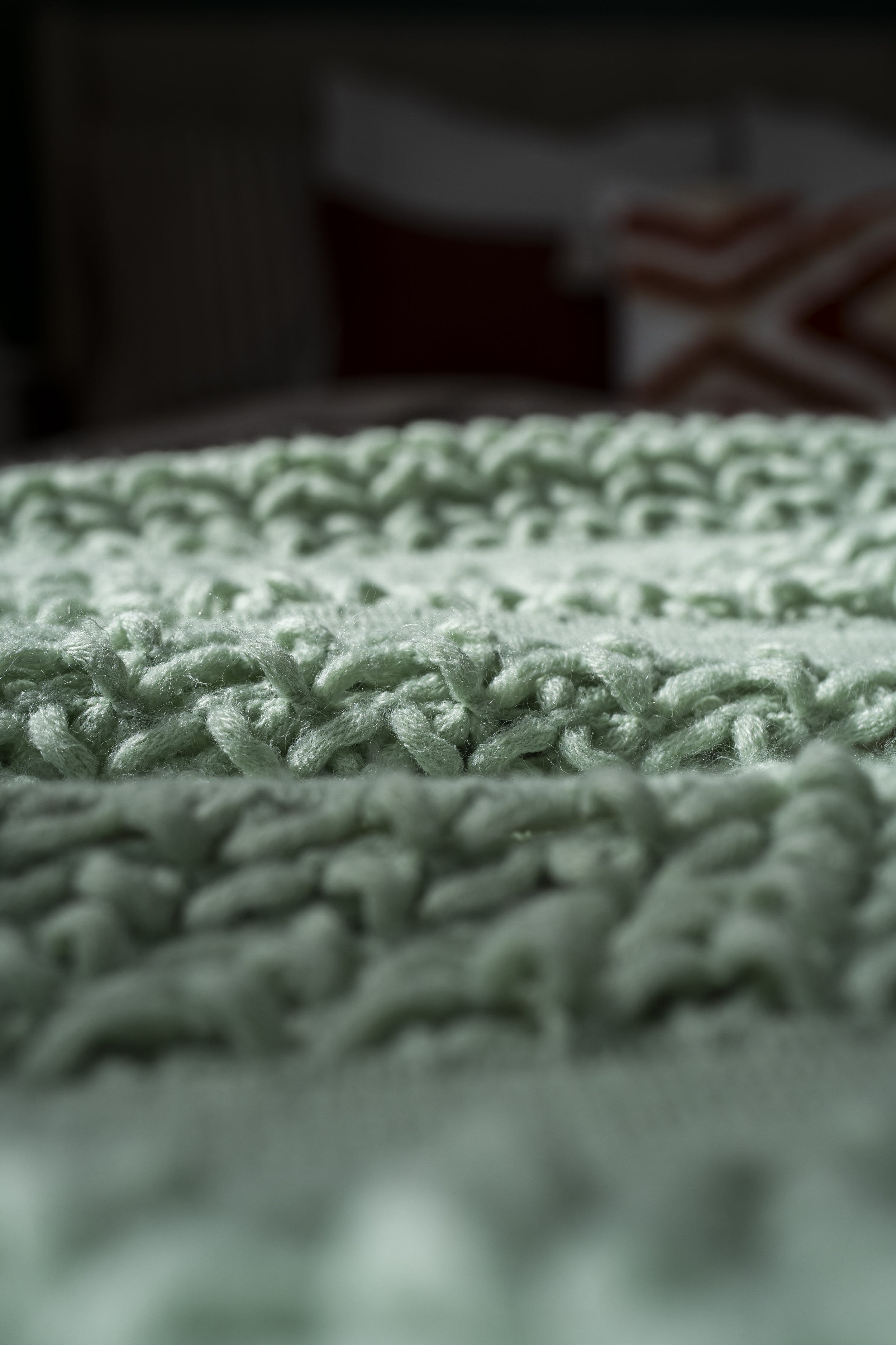 Close-up of a light green knitted fabric with a textured pattern.