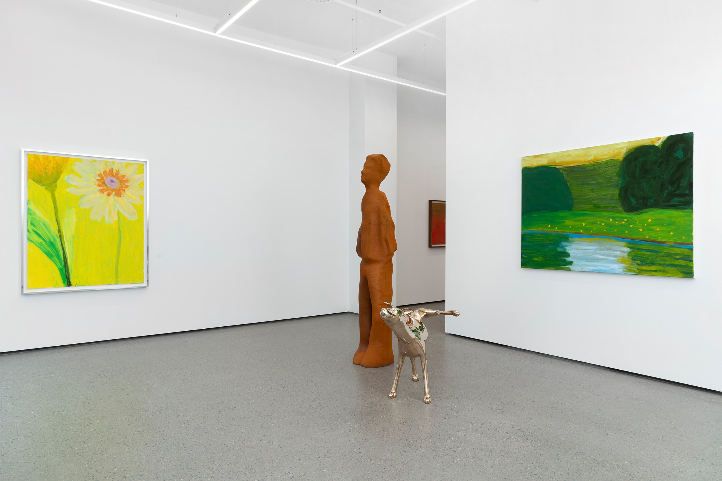 Art gallery with white walls, featuring two paintings on separate walls, one landscape and one floral, a wooden sculpture of a woman, and a shiny metallic dog sculpture in the center.