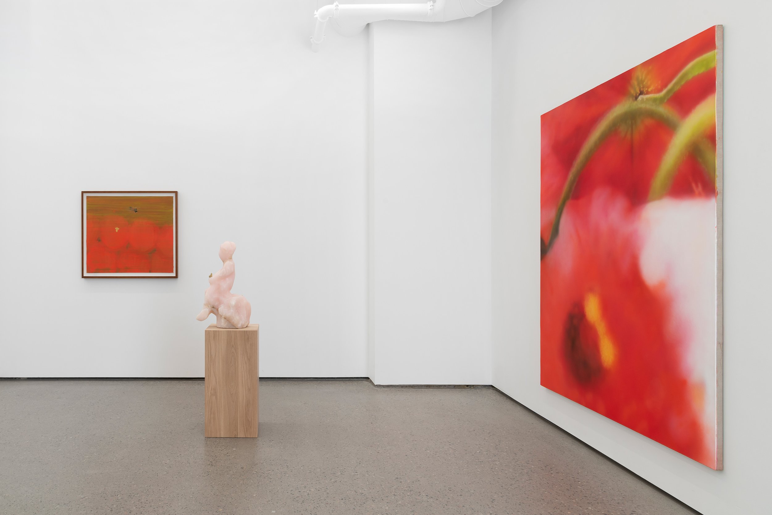 An art gallery featuring two abstract paintings on white walls, with a sculpture on a wooden pedestal in a minimalist setting.