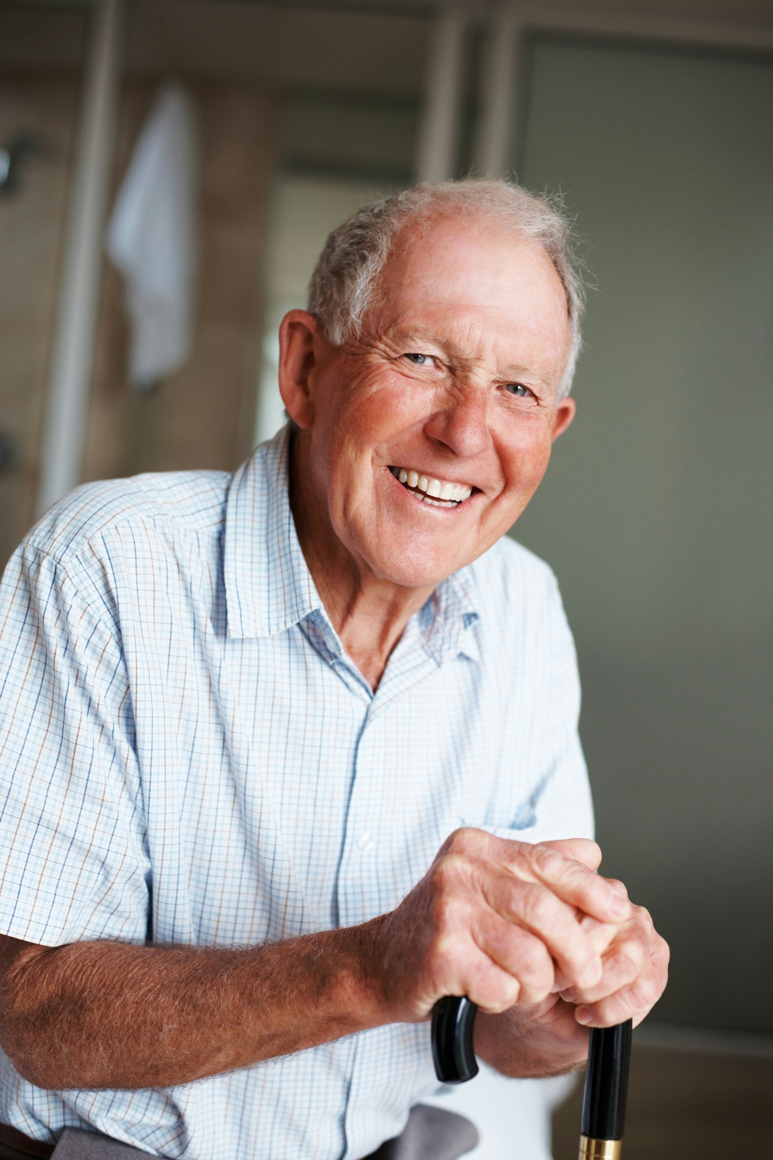 man smiling with cane in button down shirt