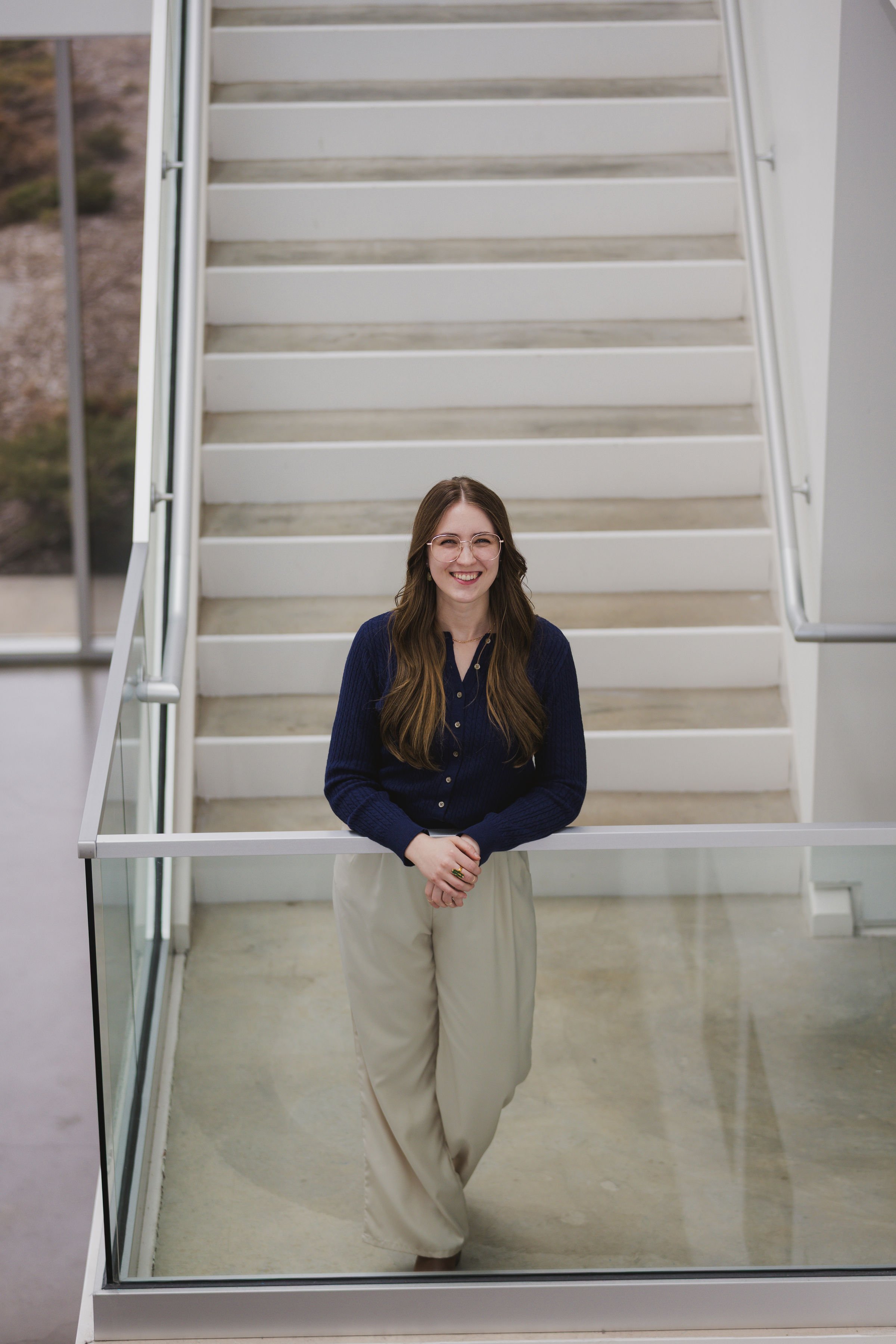 woman named Ella wearing a blue shirt and white pants standing and smiling