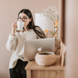 woman drinking coffee and standing by computer