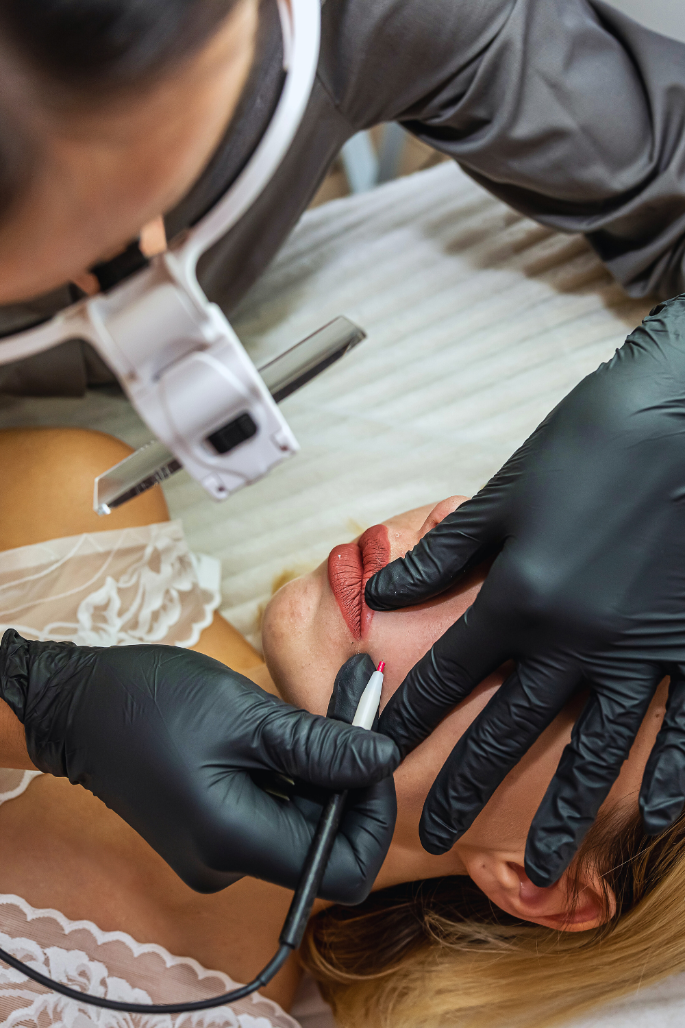electrologist wearing black gloves doing electroysis on a woman's facee