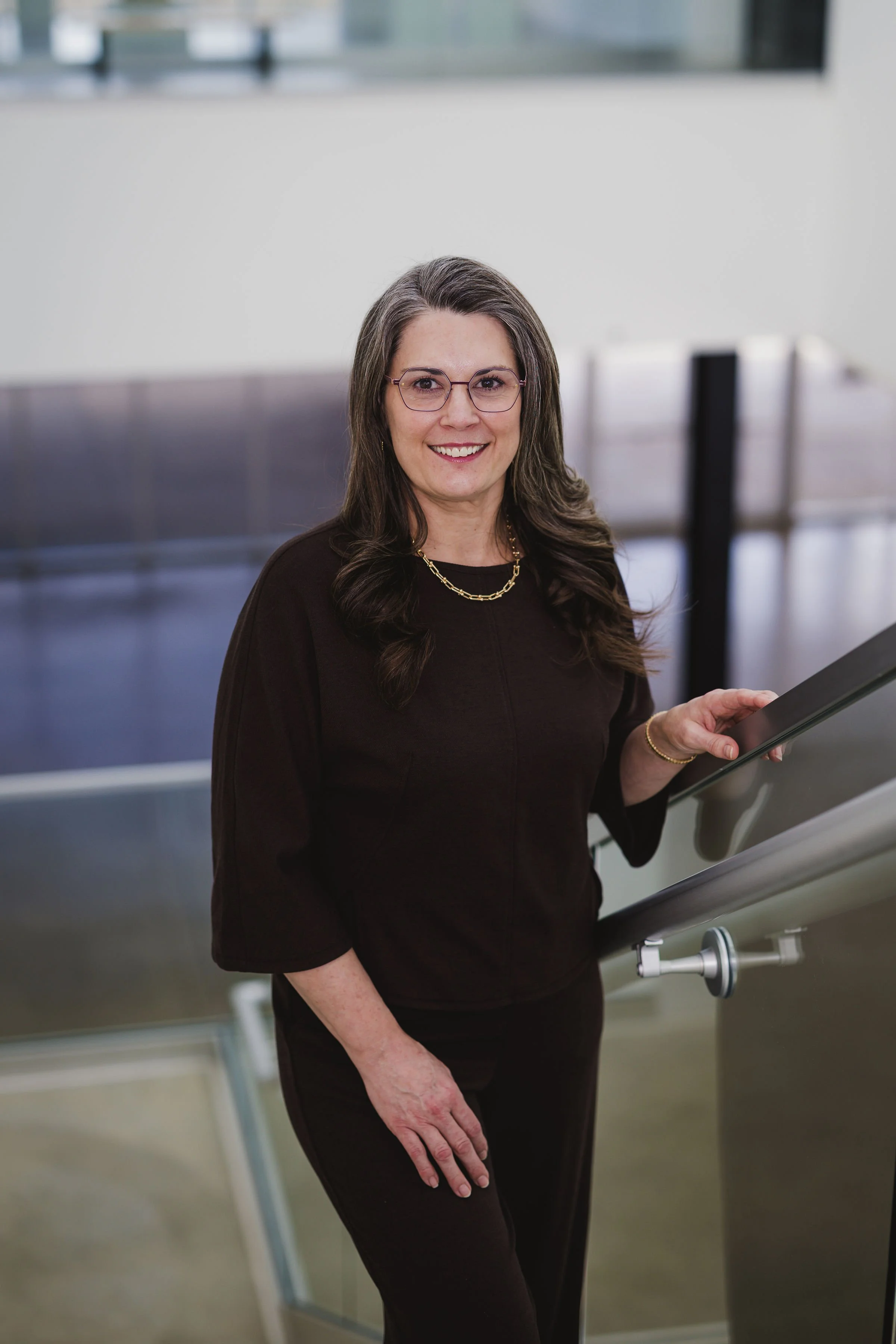 a woman named heidi standing on a staircase wearing brown smiling