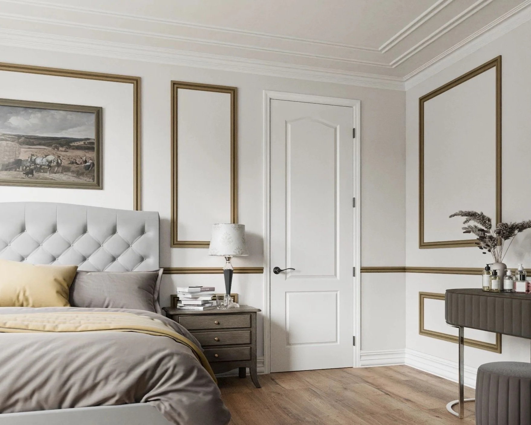 A bedroom with white walls decorated with gold rectangular trim, featuring a white door, a bedside table with a lamp, and a bed with beige and gray bedding and pillows.