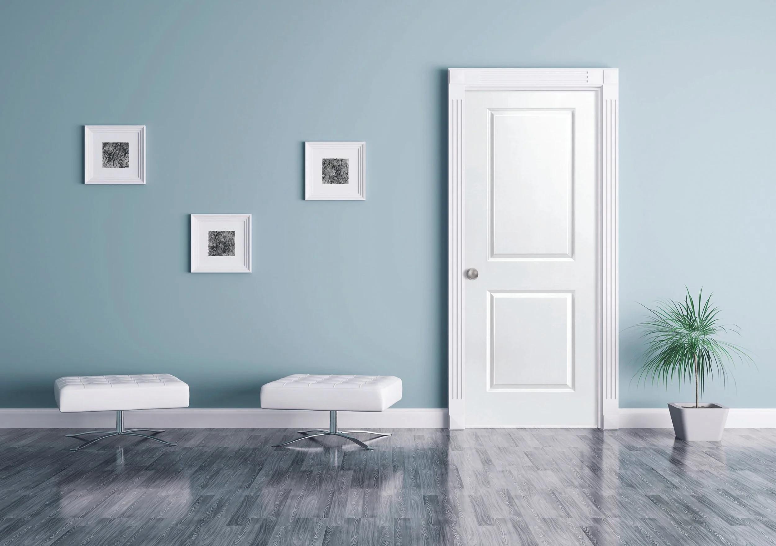 A minimalist room with light blue walls, a white door, and a gray wooden floor. There are three small framed black and white pictures on the wall, two white modern cushioned stools, and a potted plant to the right of the door.