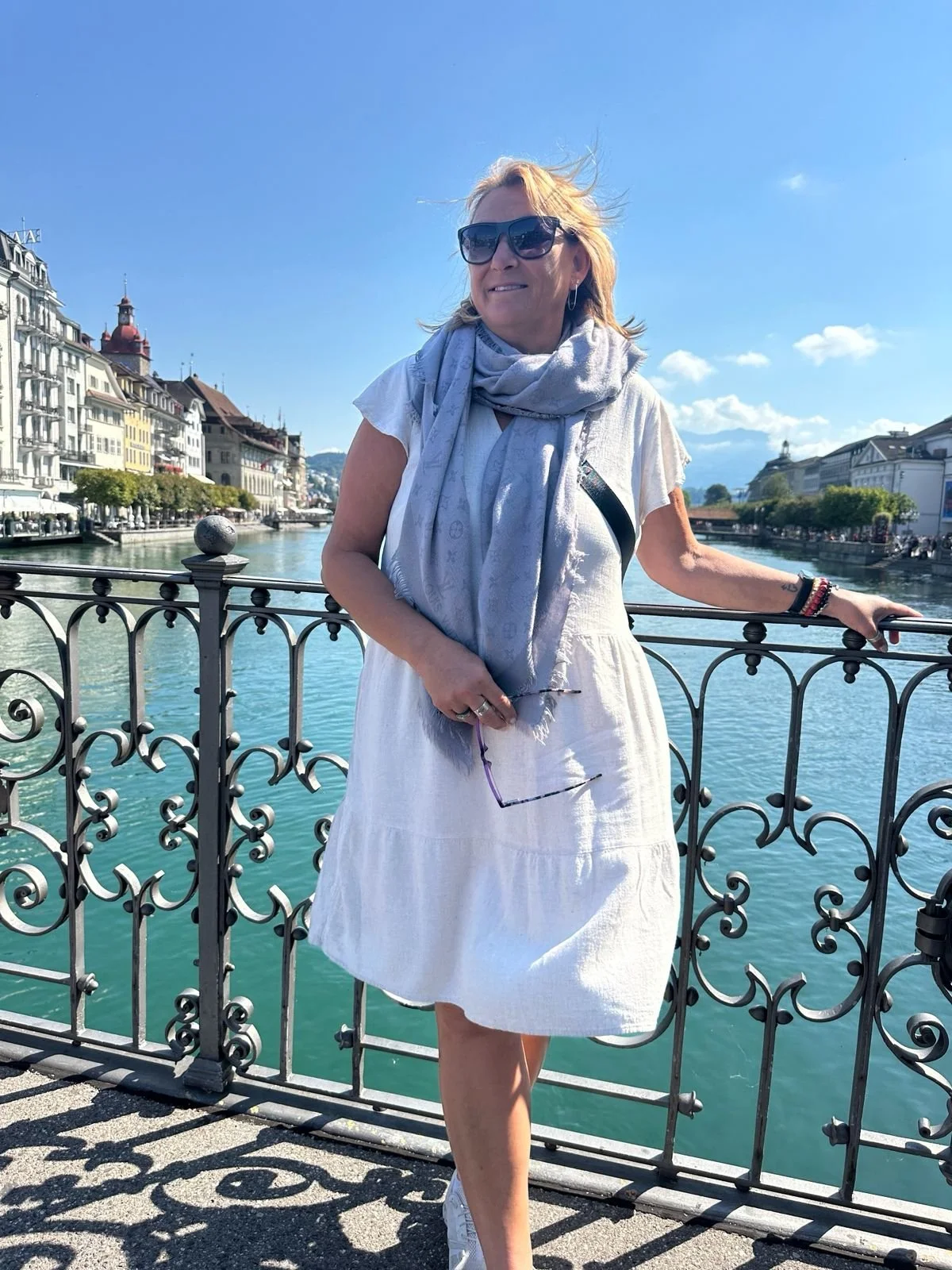 A woman wearing sunglasses and a black jacket making a peace sign with her hand in front of the Golden Gate Bridge in San Francisco, California.