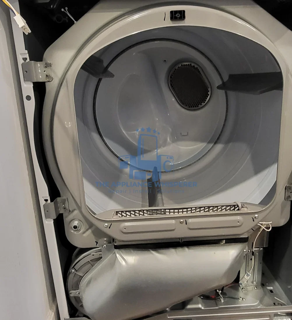 The inside of an open front-loading washing machine with a metal drum and a lint filter at the top.