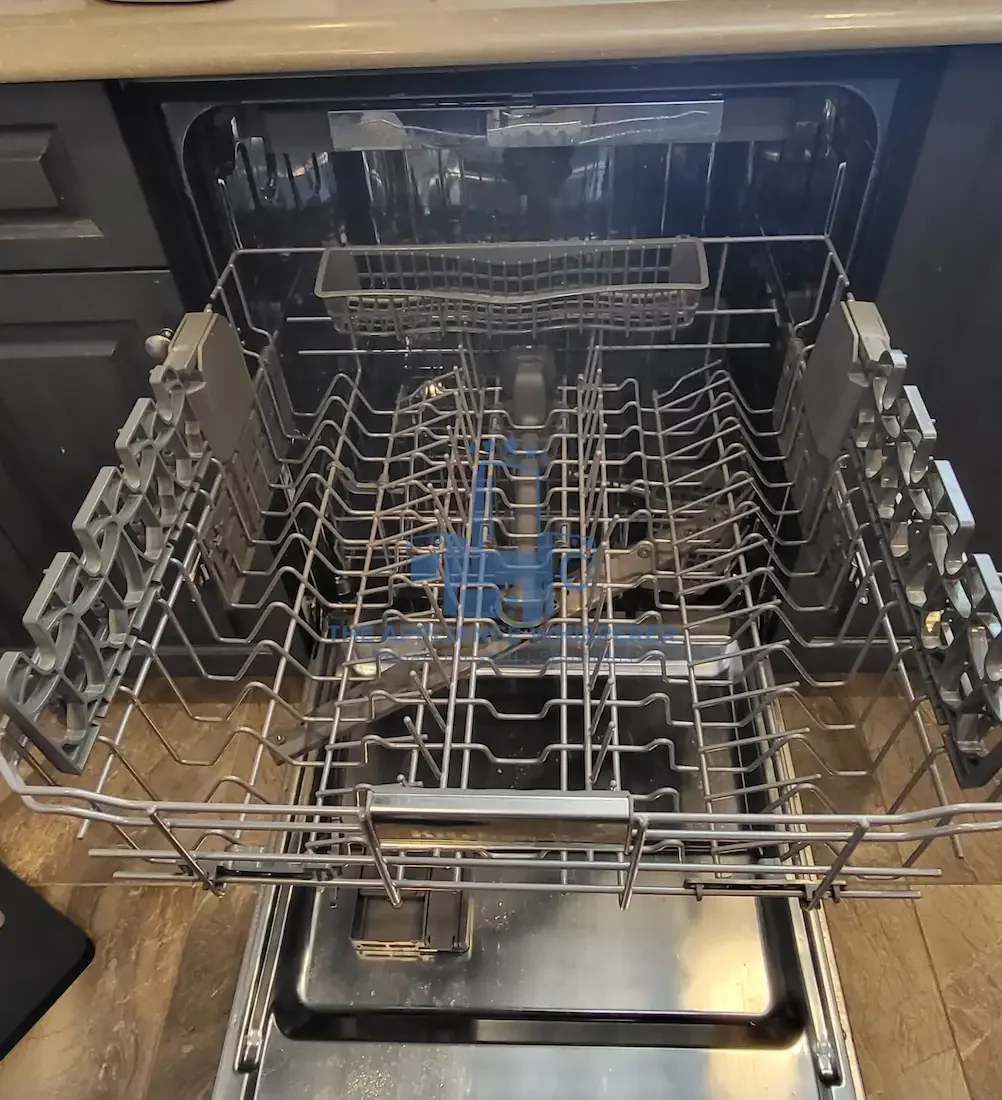 Open dishwasher with empty silver racks in kitchen setting.