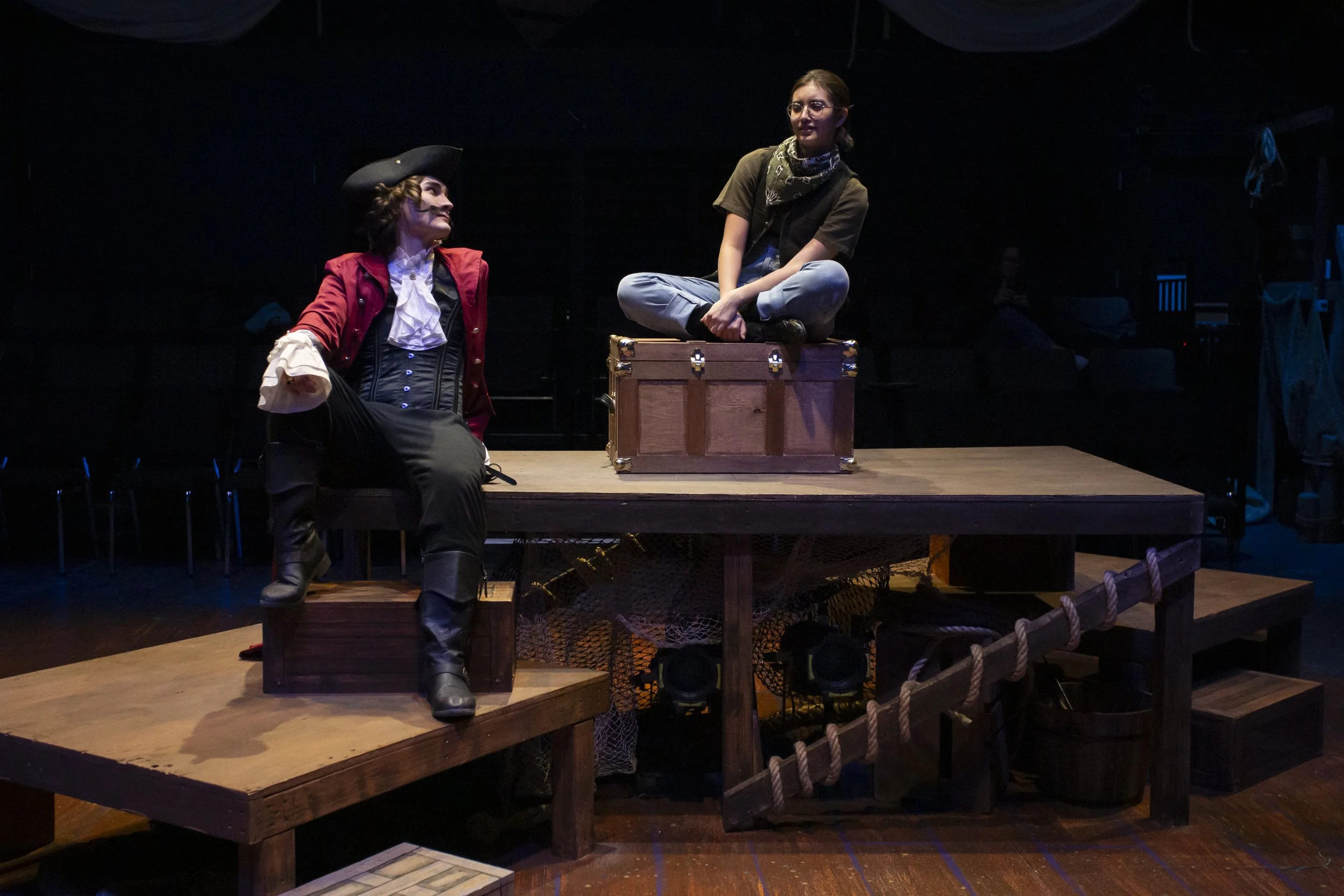 Pirate Black Stache talks to boy sitting on trunk.