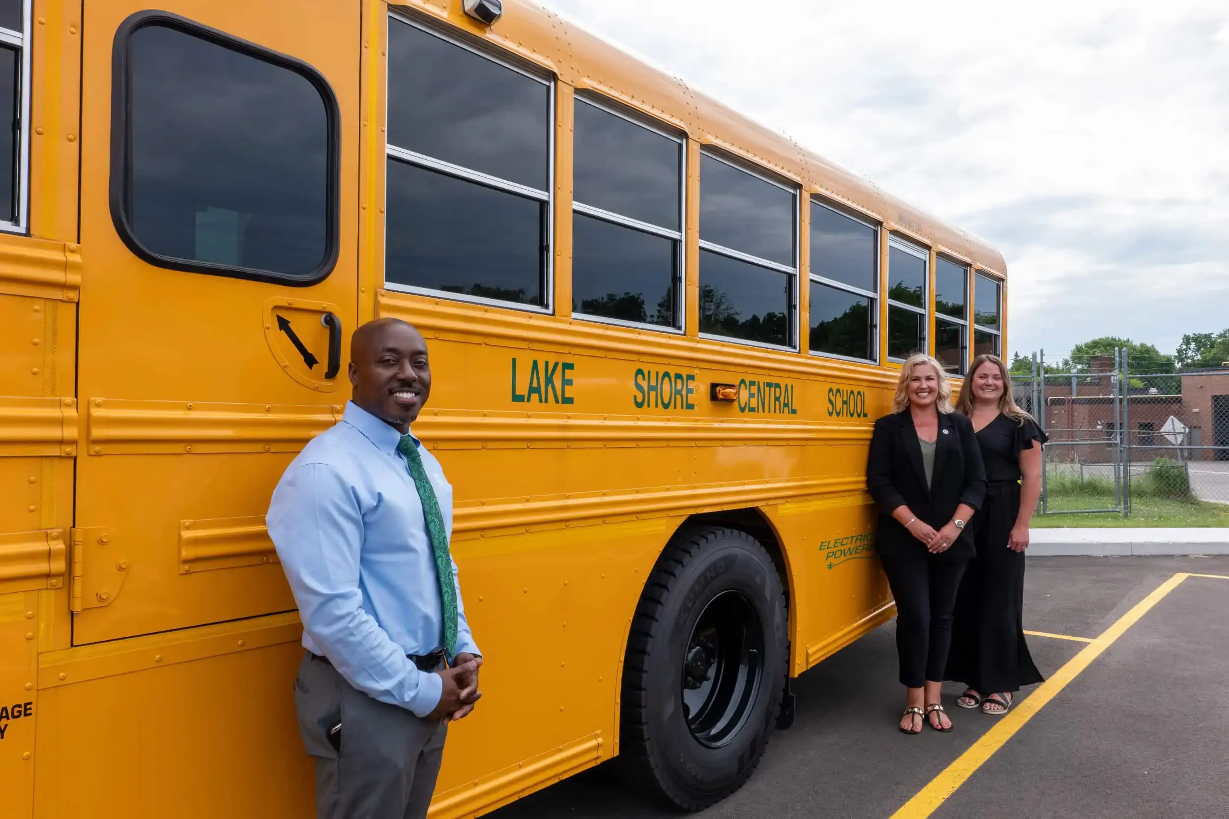 Young and Wright Architectural staff posing with an electric school bus