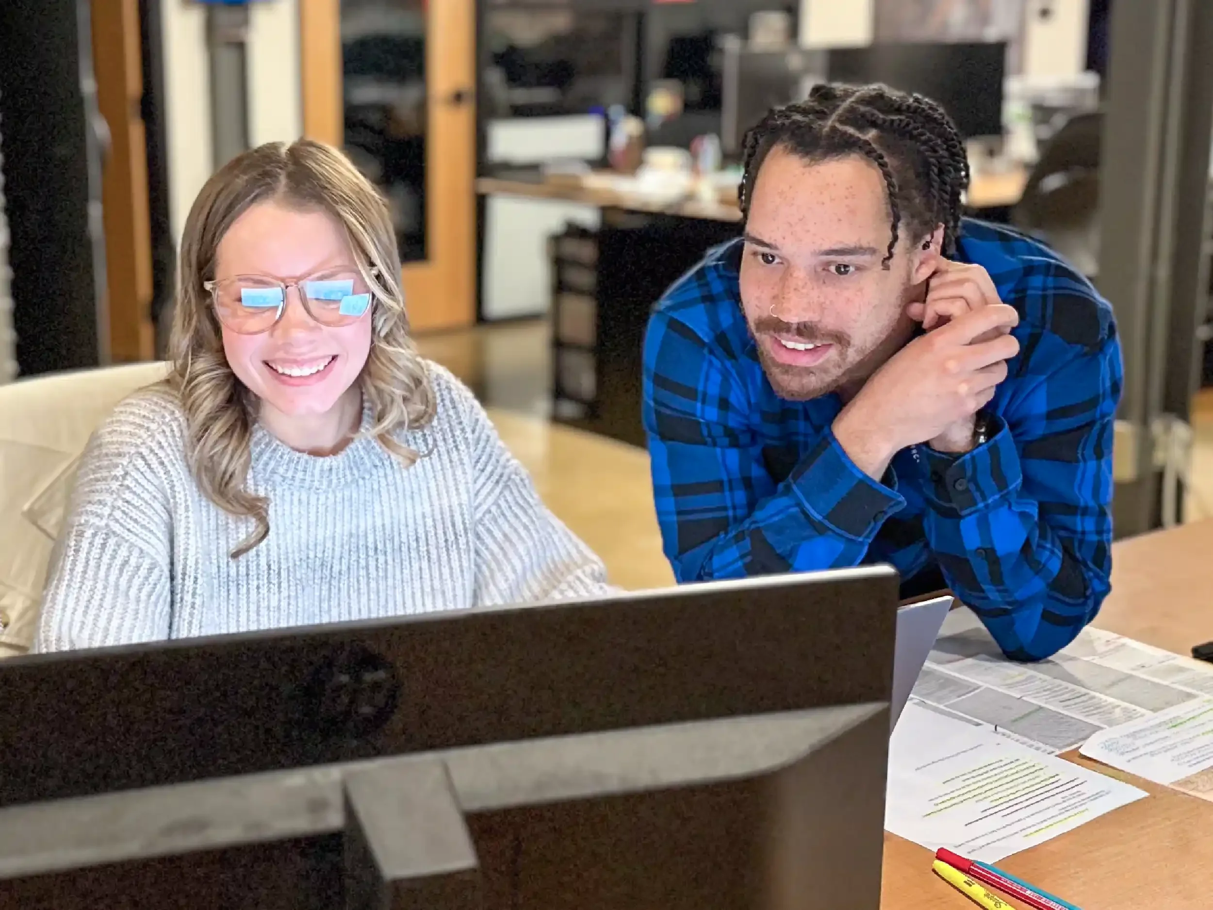 Two of the firm's architects huddled around a computer working on a project