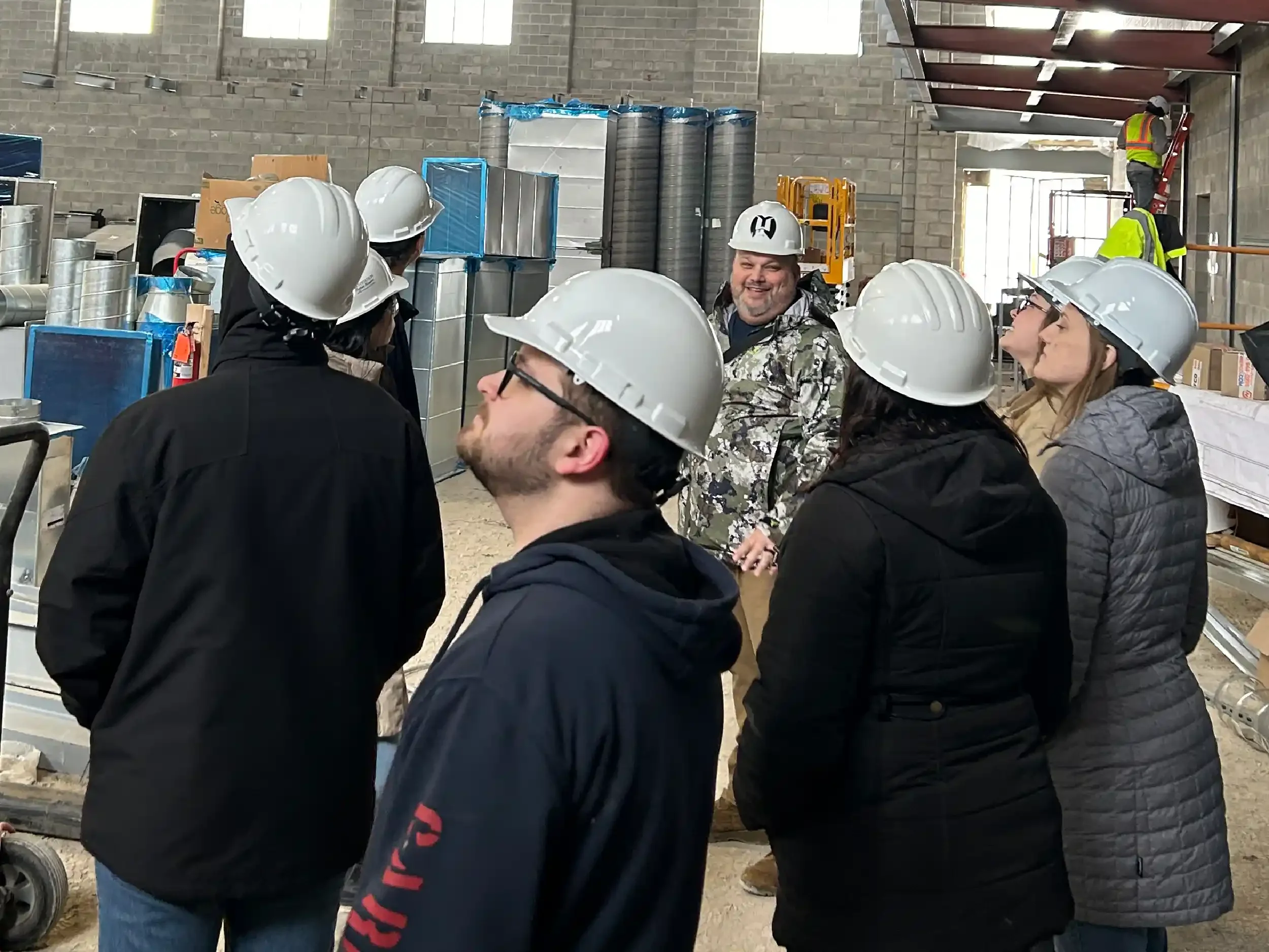 A group of Young and Wright staff members wearing hard hats during a site visit
