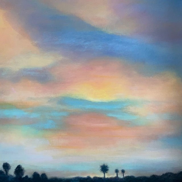 Colorful sunset skyline with pastel clouds and silhouettes of trees at the horizon.