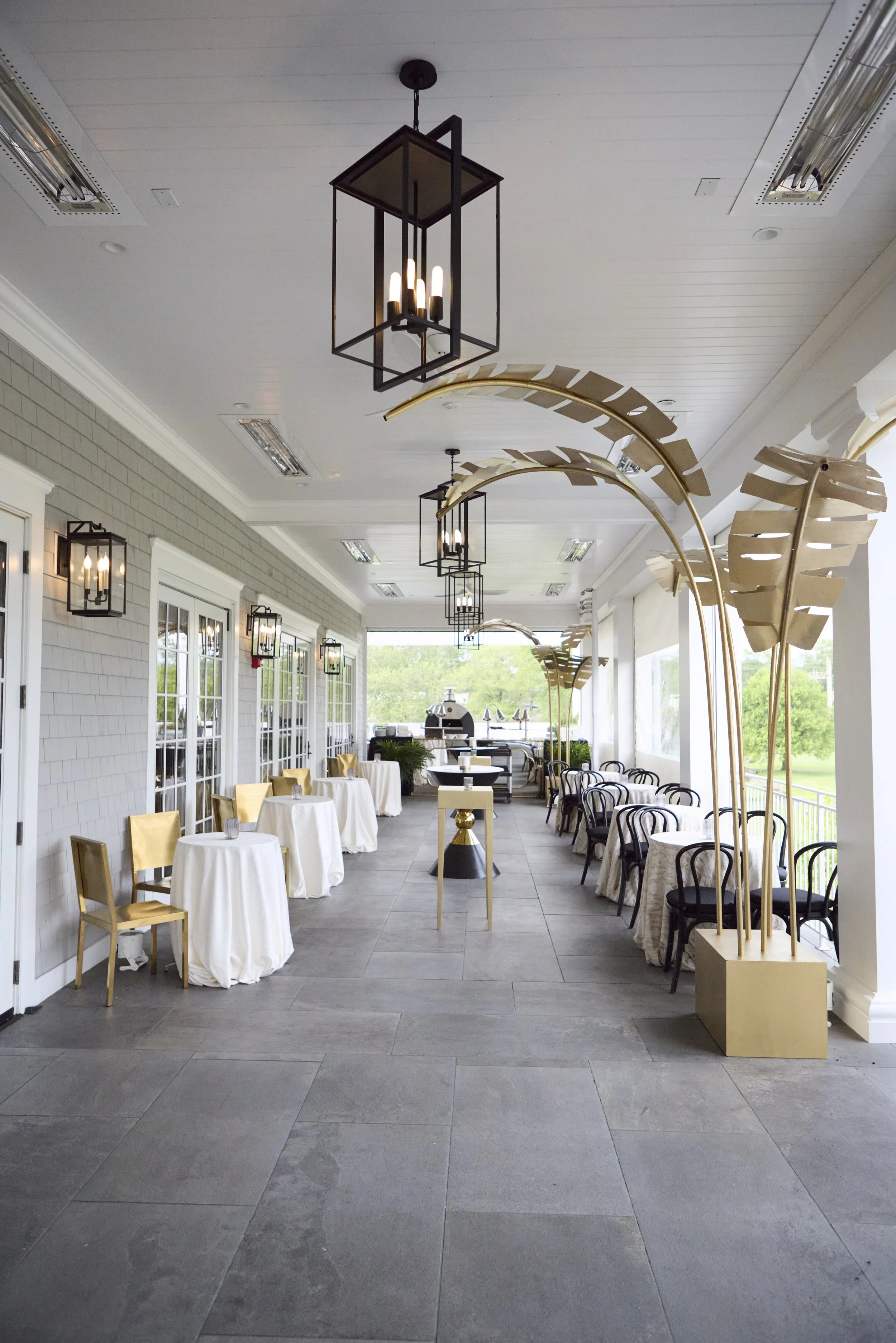 Elegant porch or patio with seating, gold and black decorative elements, large windows, and outdoor views.