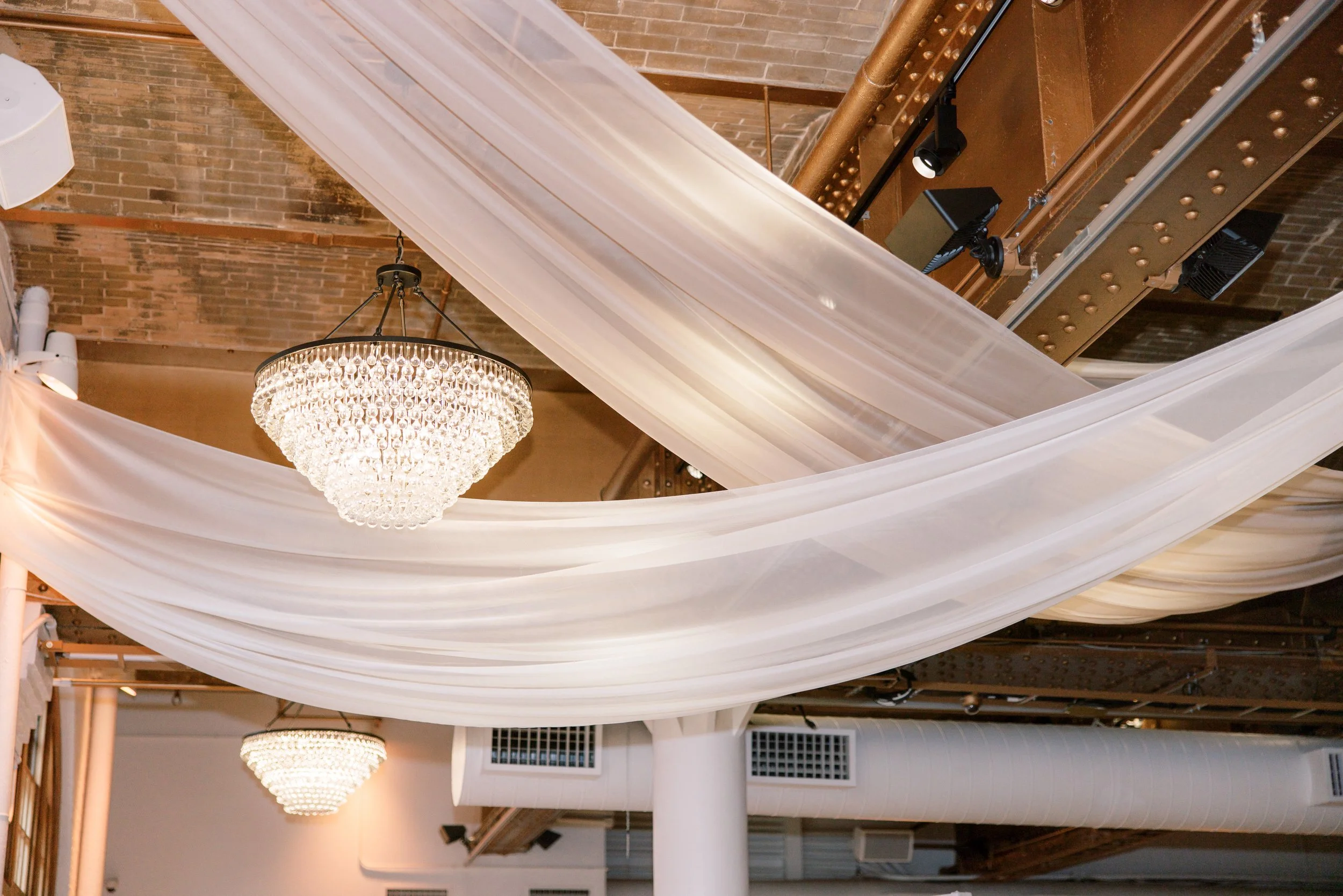 Romantic reception space with café lights and greenery under soft draped fabric ceilings at the Altman Building in Chelsea NYC.