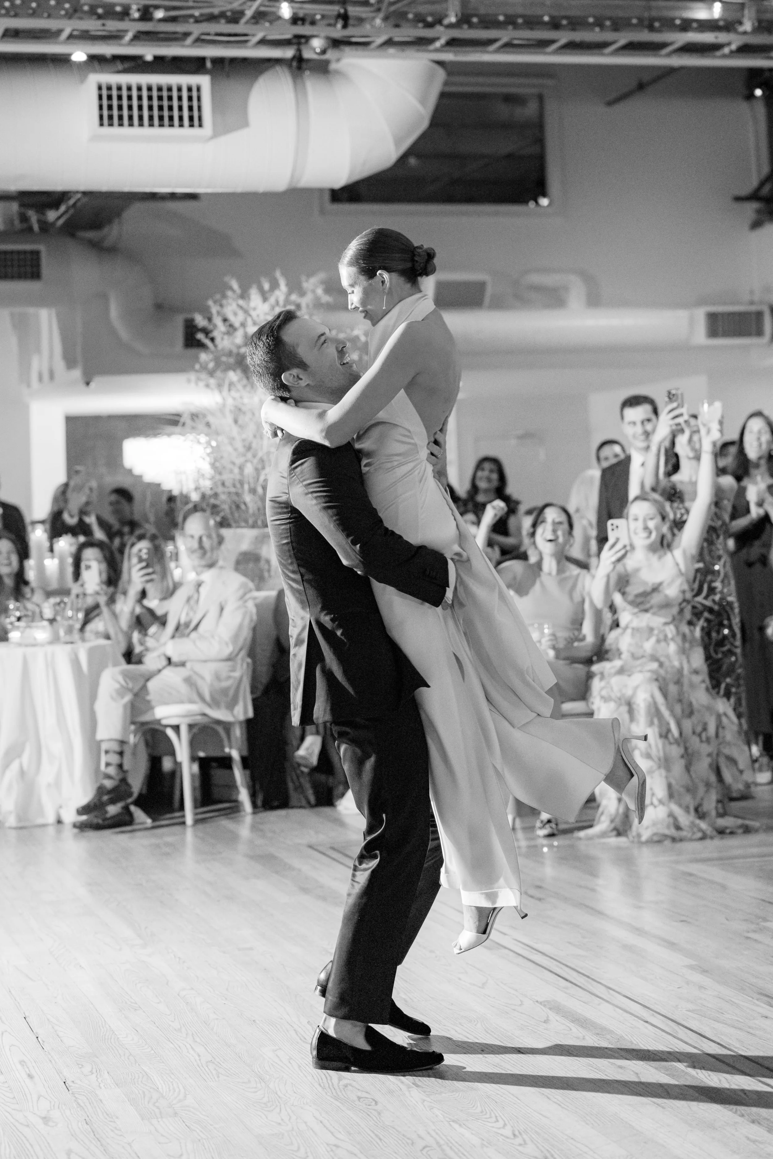 Black and white photo of bride and groom celebrating during their first dance at the Altman Building wedding.