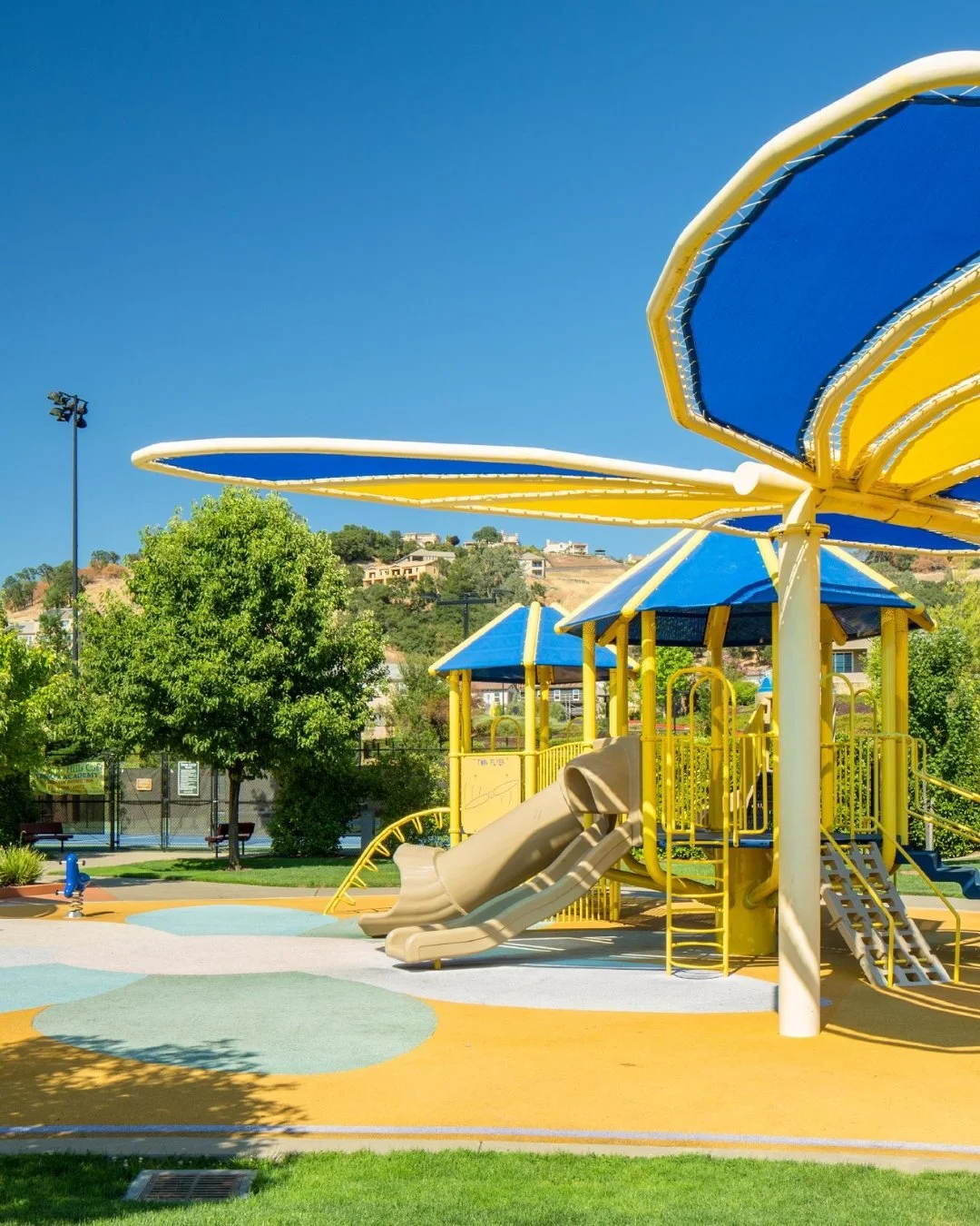 Colorful playground and splash pad at Promontory Park in El Dorado Hills, California, featuring slides, shade structures, and family recreation.