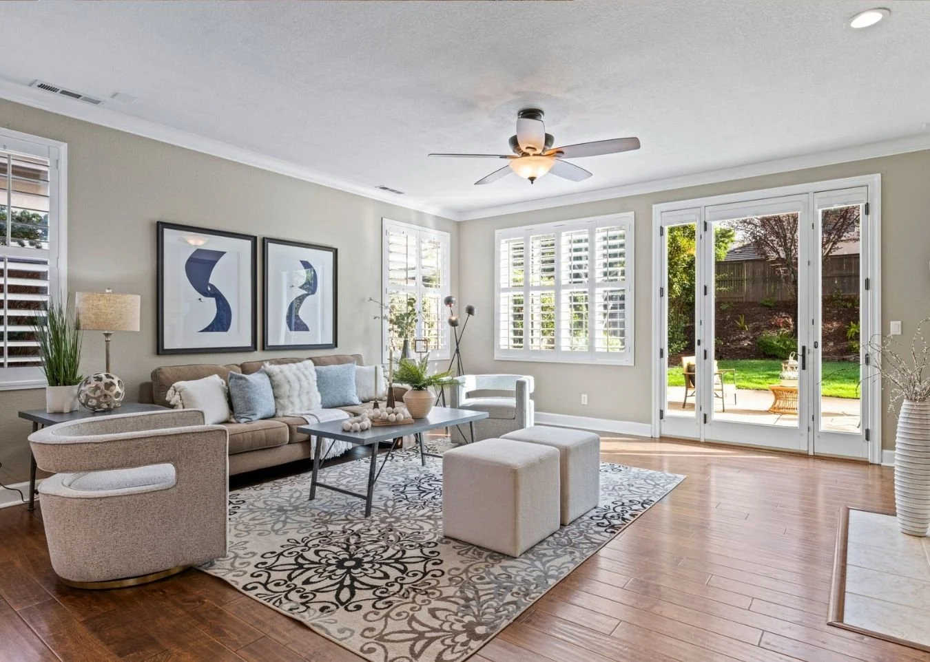 Modern open-concept living room with bar seating, stylish lounge chairs, and seamless indoor-outdoor flow to landscaped backyard in a luxury California home.