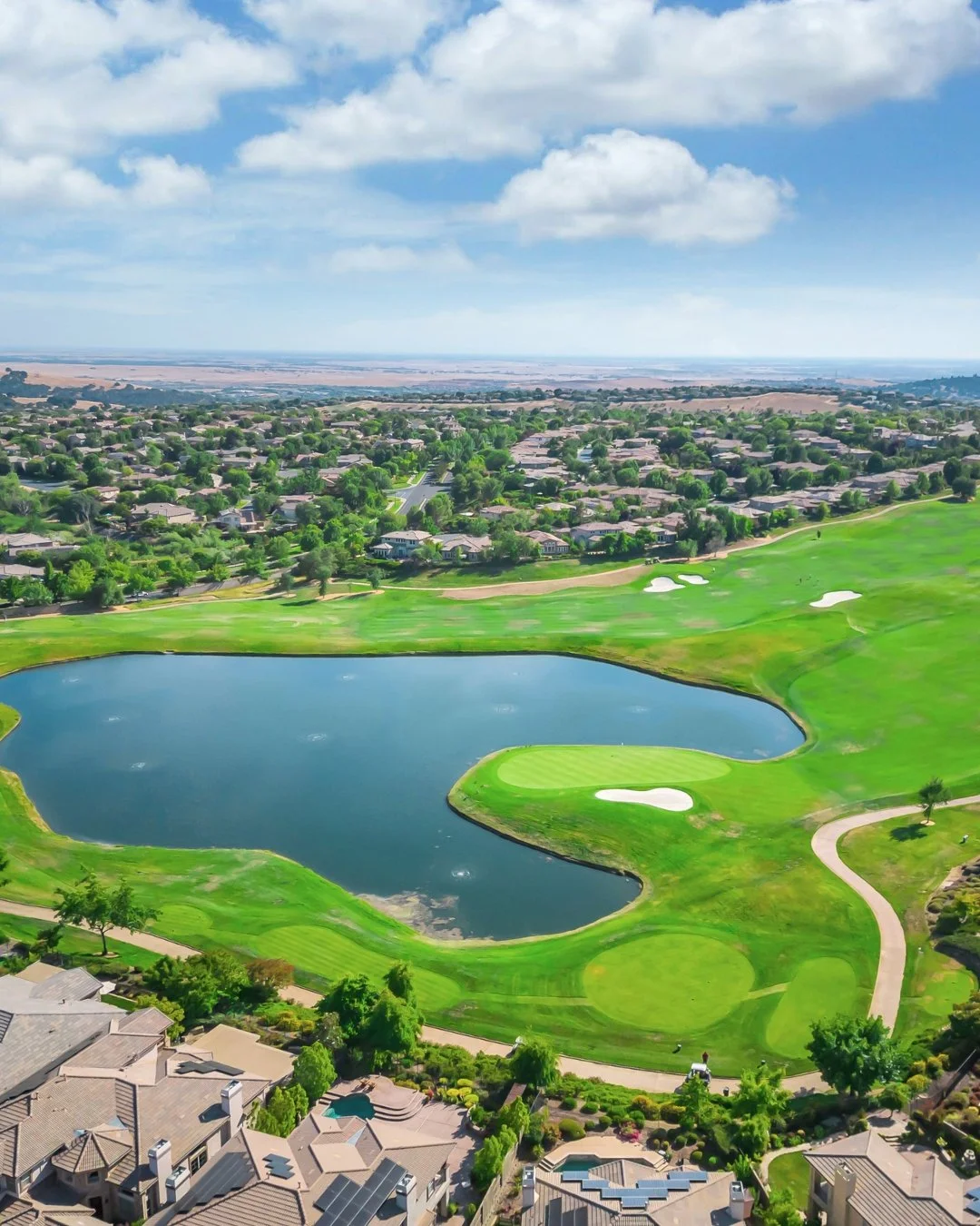Aerial view of Serrano Country Club golf course and homes in El Dorado Hills, California with lake, fairways, and luxury real estate.