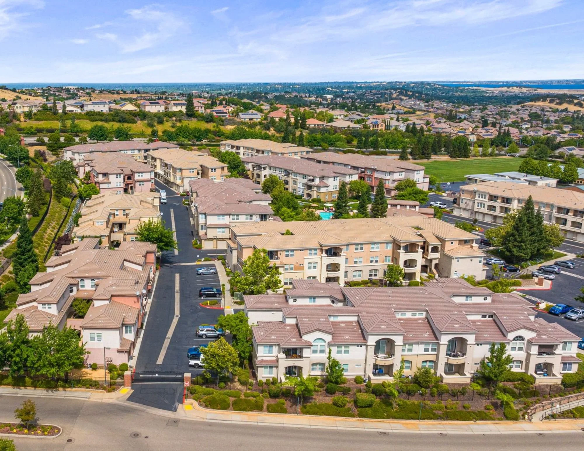 Aerial view of Folsom, California condo and townhome community near parks and foothill neighborhoods, showcasing residential real estate and surrounding landscape.